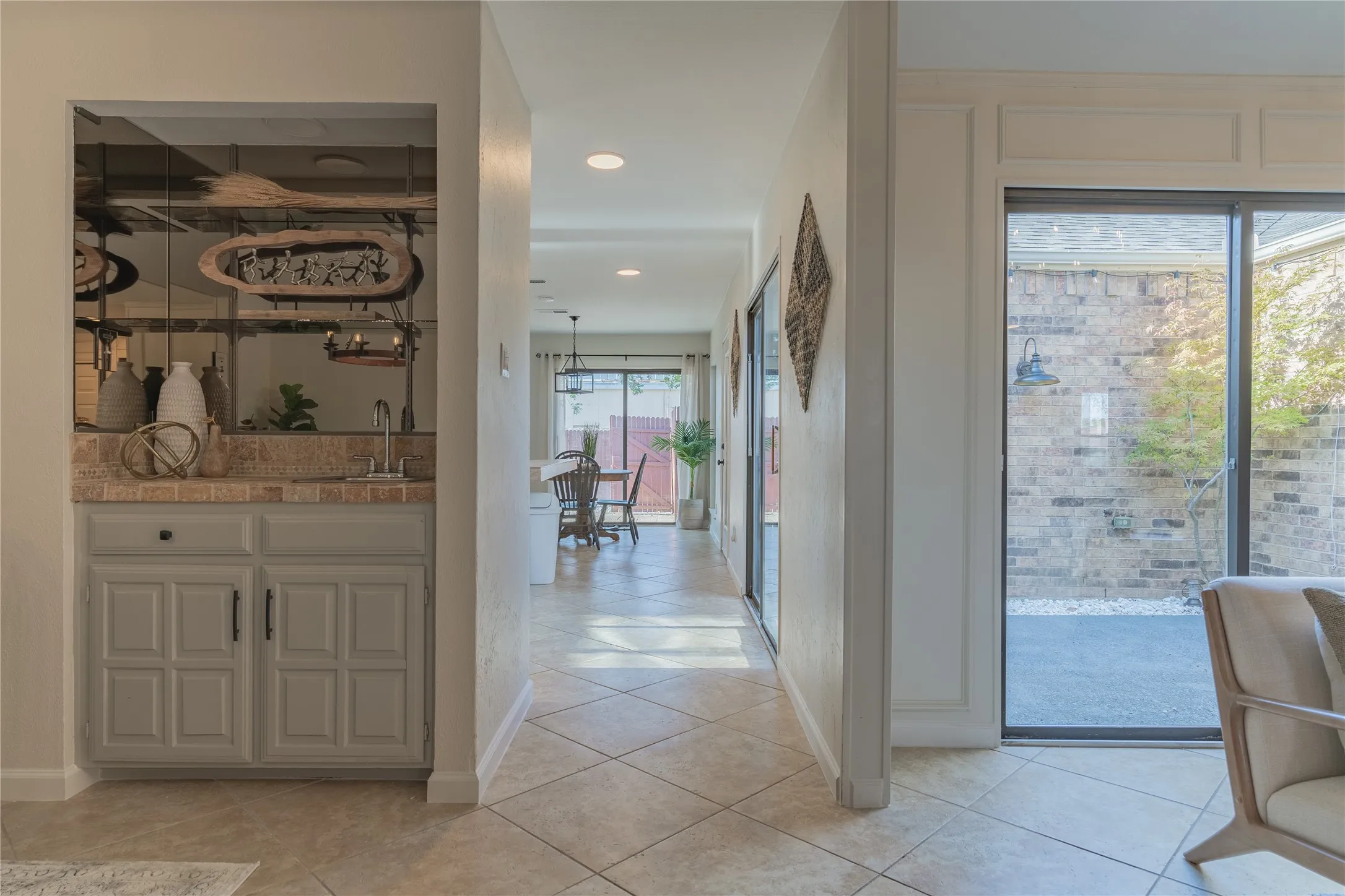 Built-in wet bar with a single basin sink, light-colored cabinetry, and mirrored backsplash