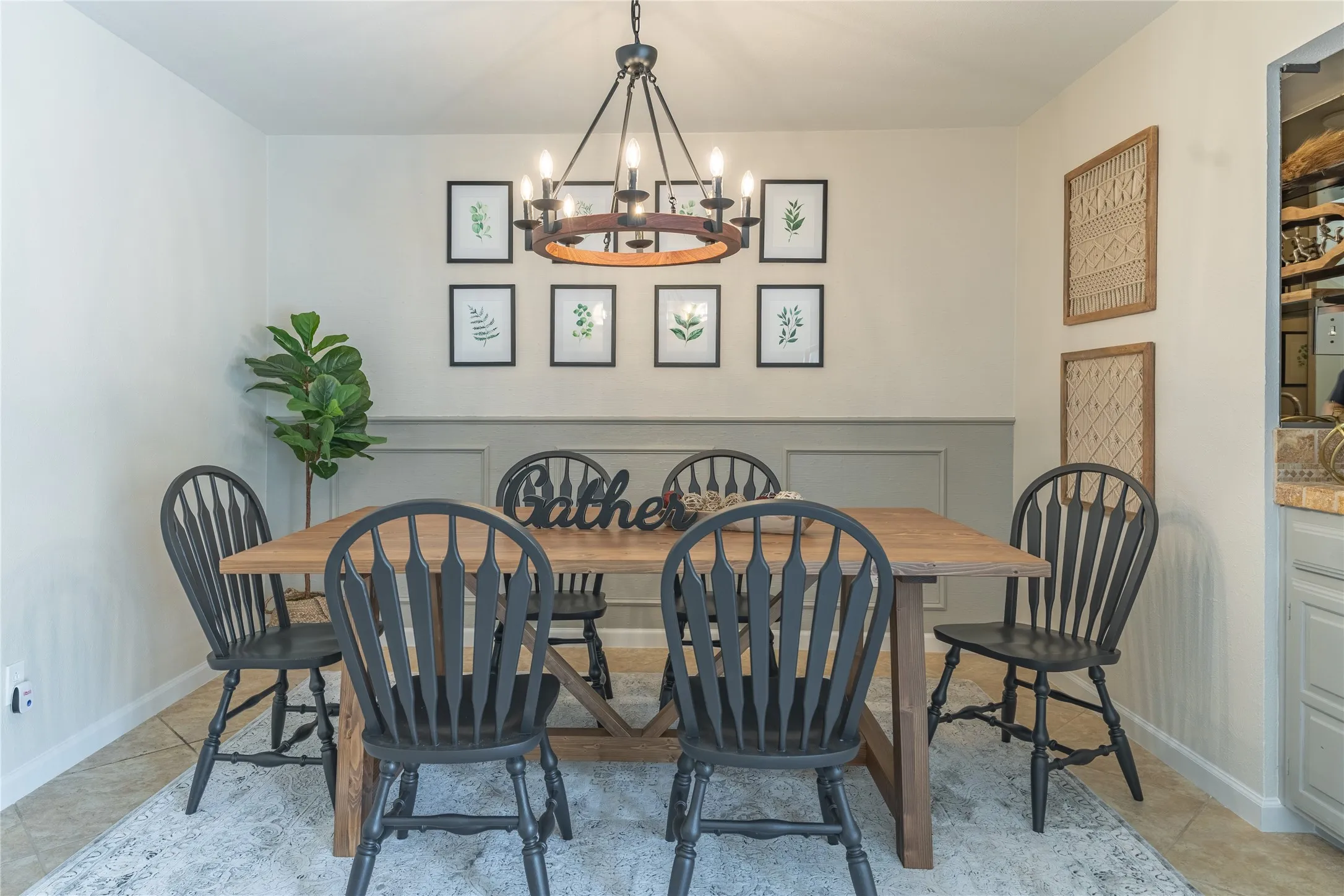 Wainscoting paneling, tile flooring, and an overhead chandelier with a circular wood-tone accent