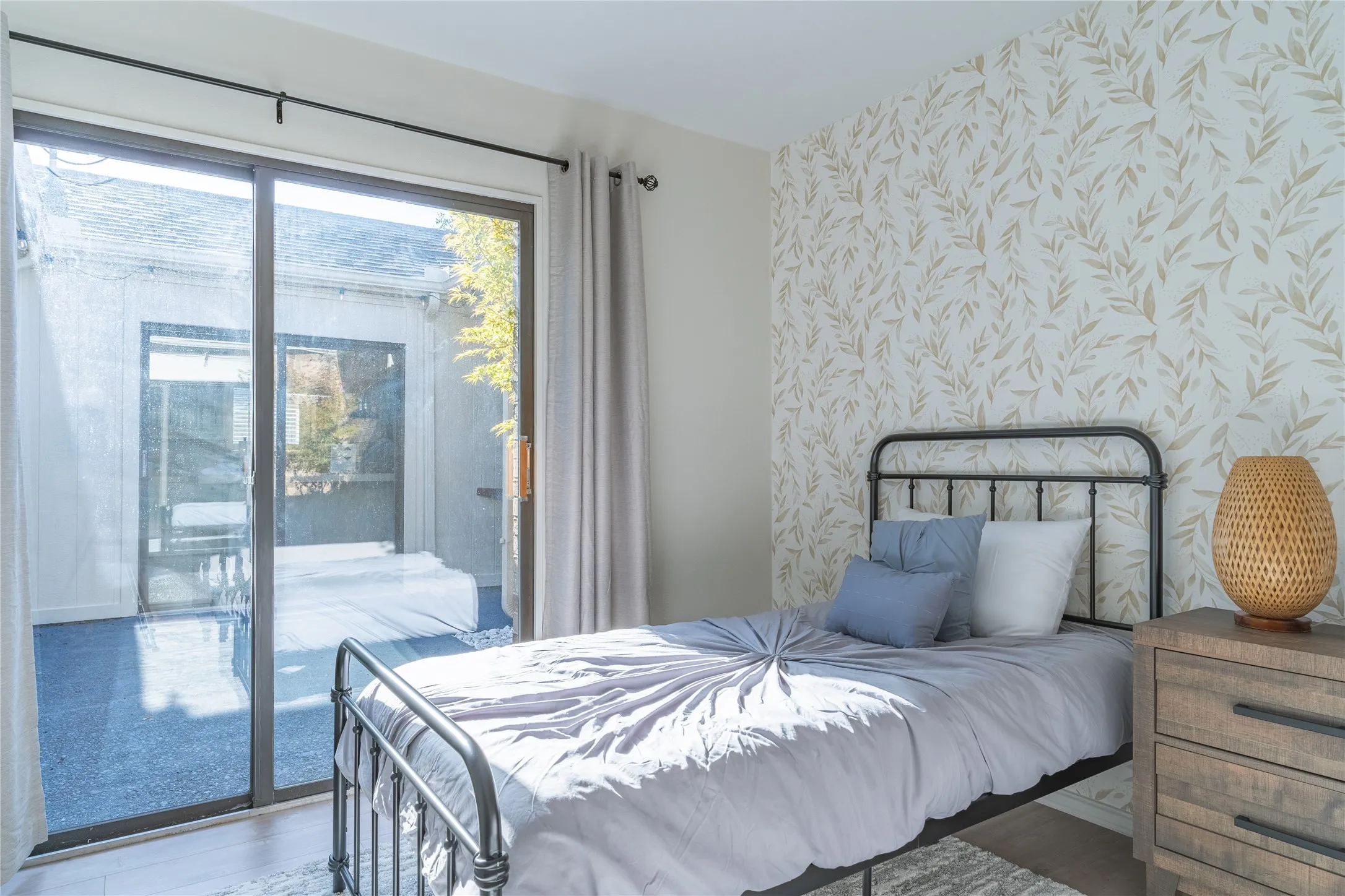 Sliding glass door leading to an outdoor space, decorative accent wall, wood-finish flooring