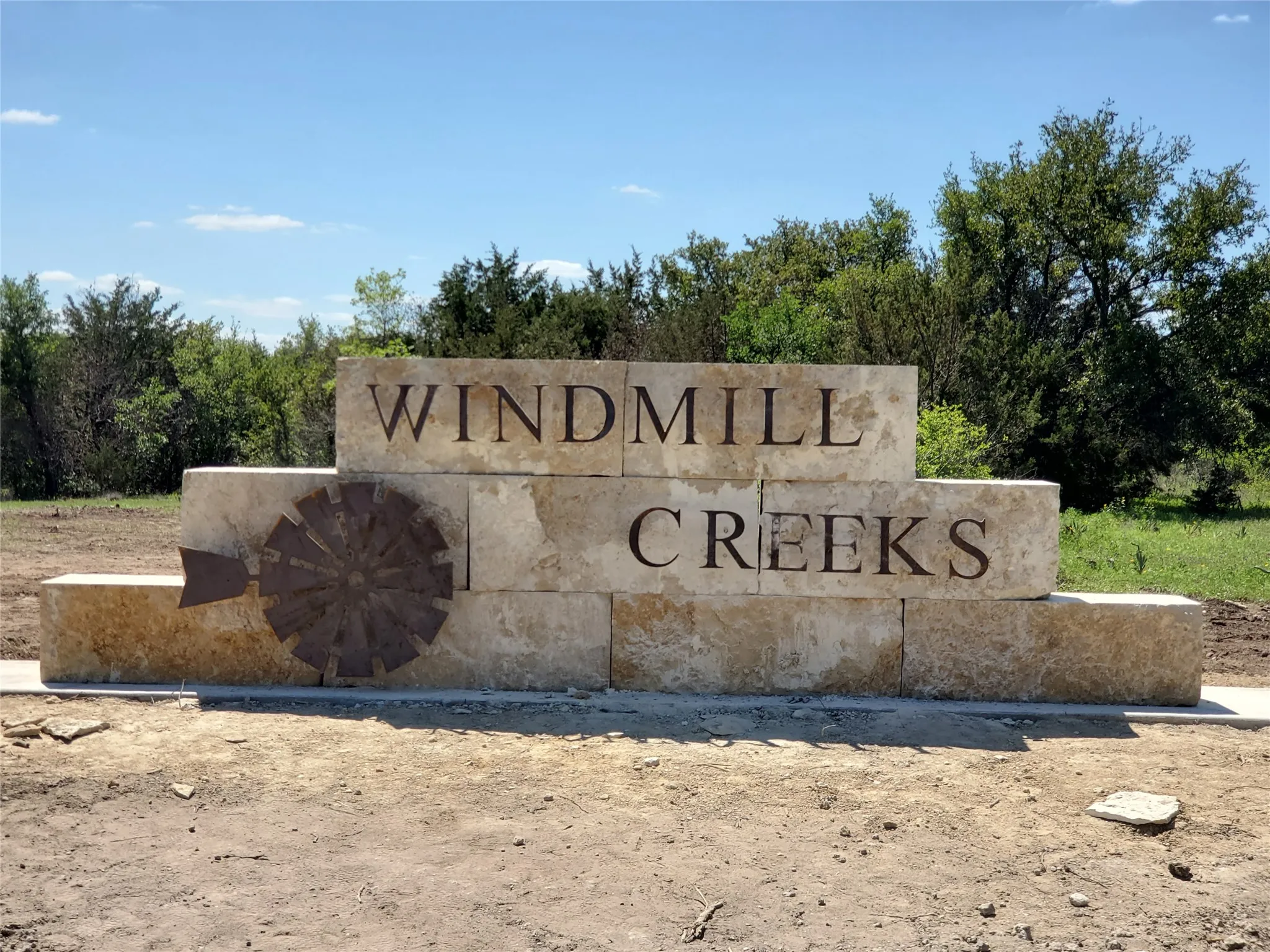 Stone entrance monument featuring engraved lettering and an integrated metal windmill emblem
