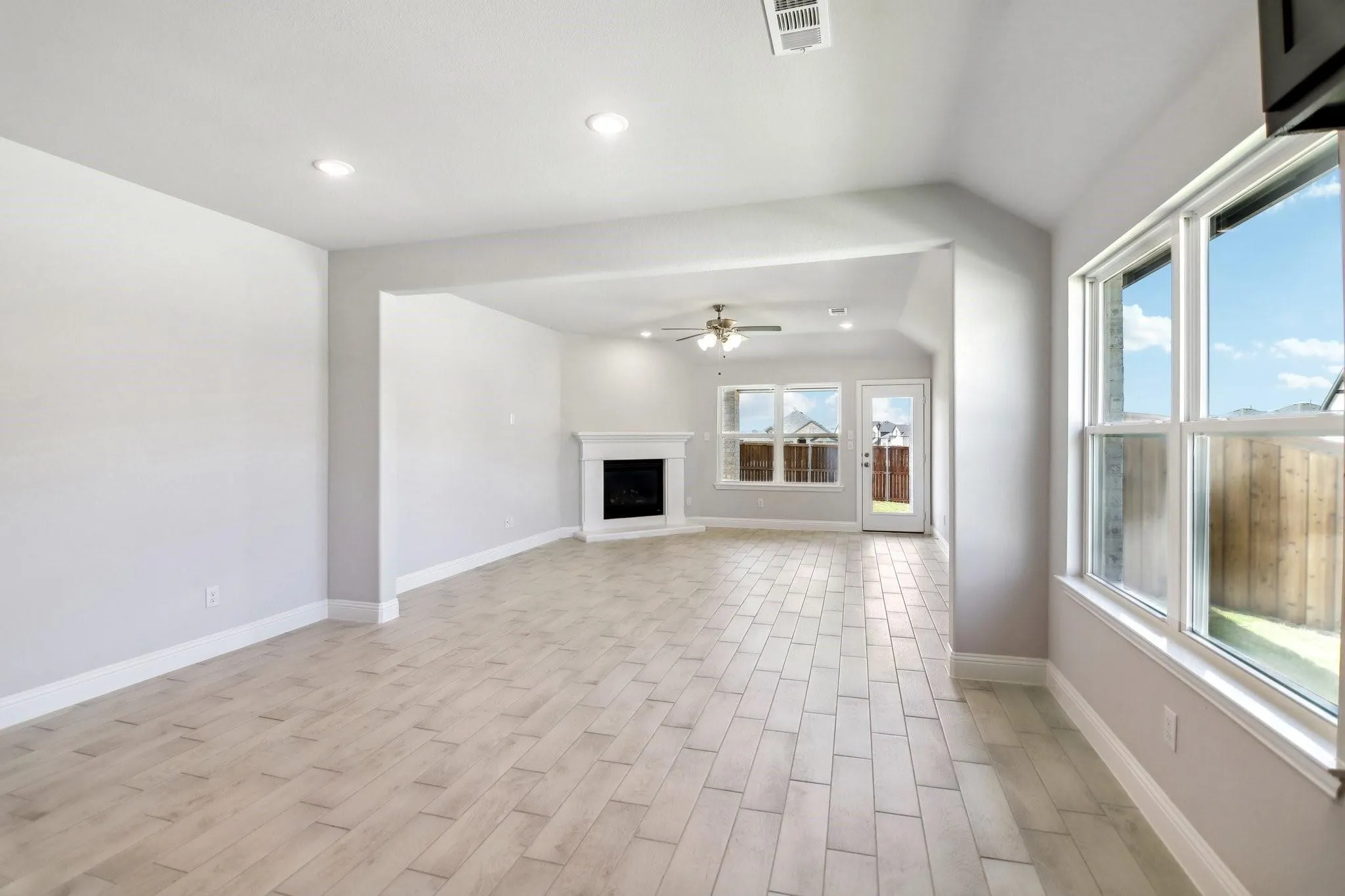 Recessed lighting, wood-finish flooring, white mantel, ceiling fan, and multiple windows