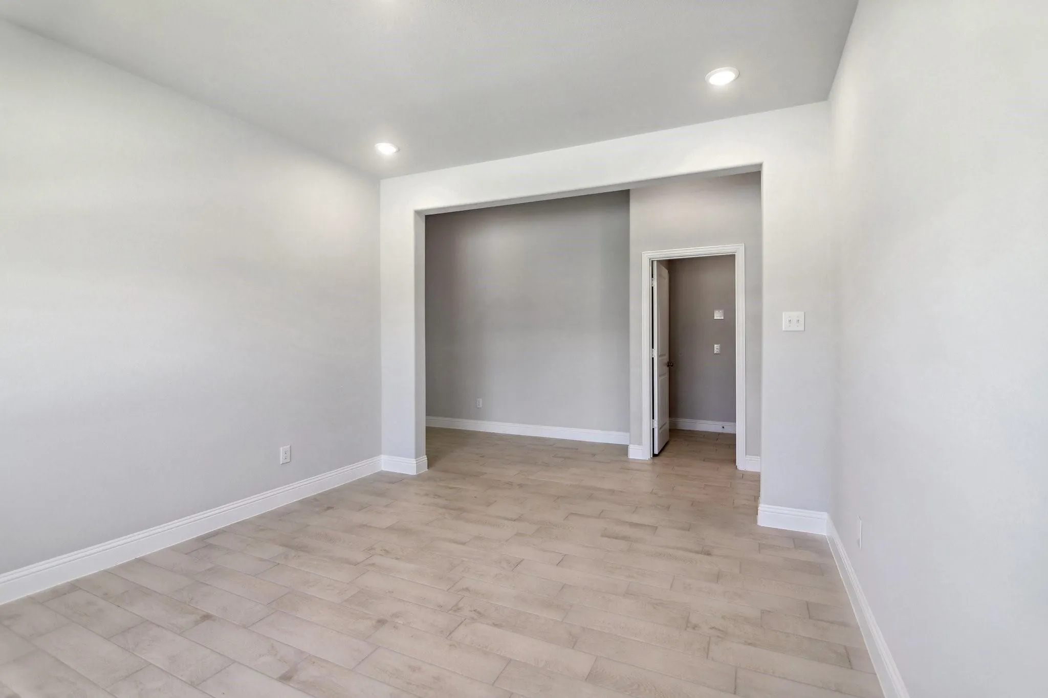 Recessed lighting illuminates the space, featuring wood-finish flooring and light-toned walls
