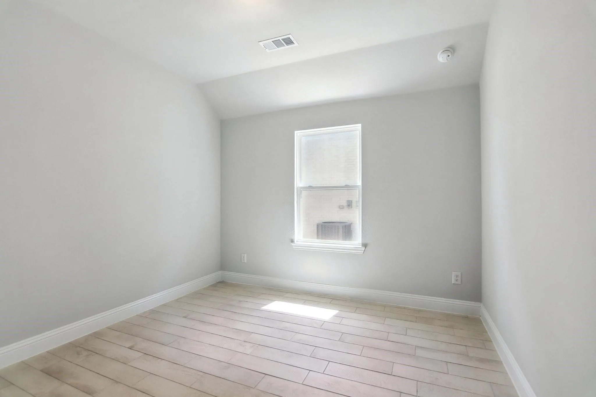 Neutral tone wall paint, wood-finish flooring, single window, and white trim molding