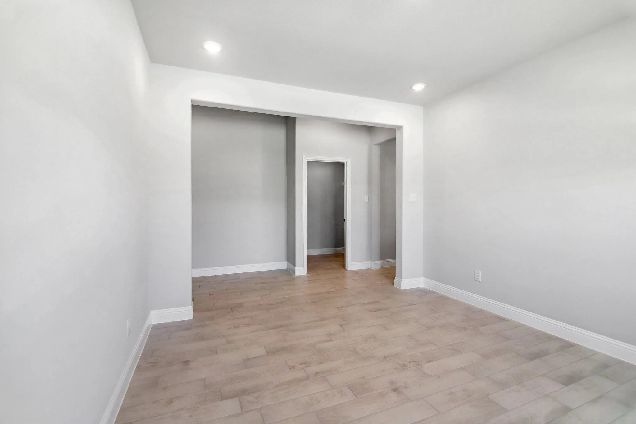 Spacious room featuring wood-finish flooring, recessed lighting, and white baseboards