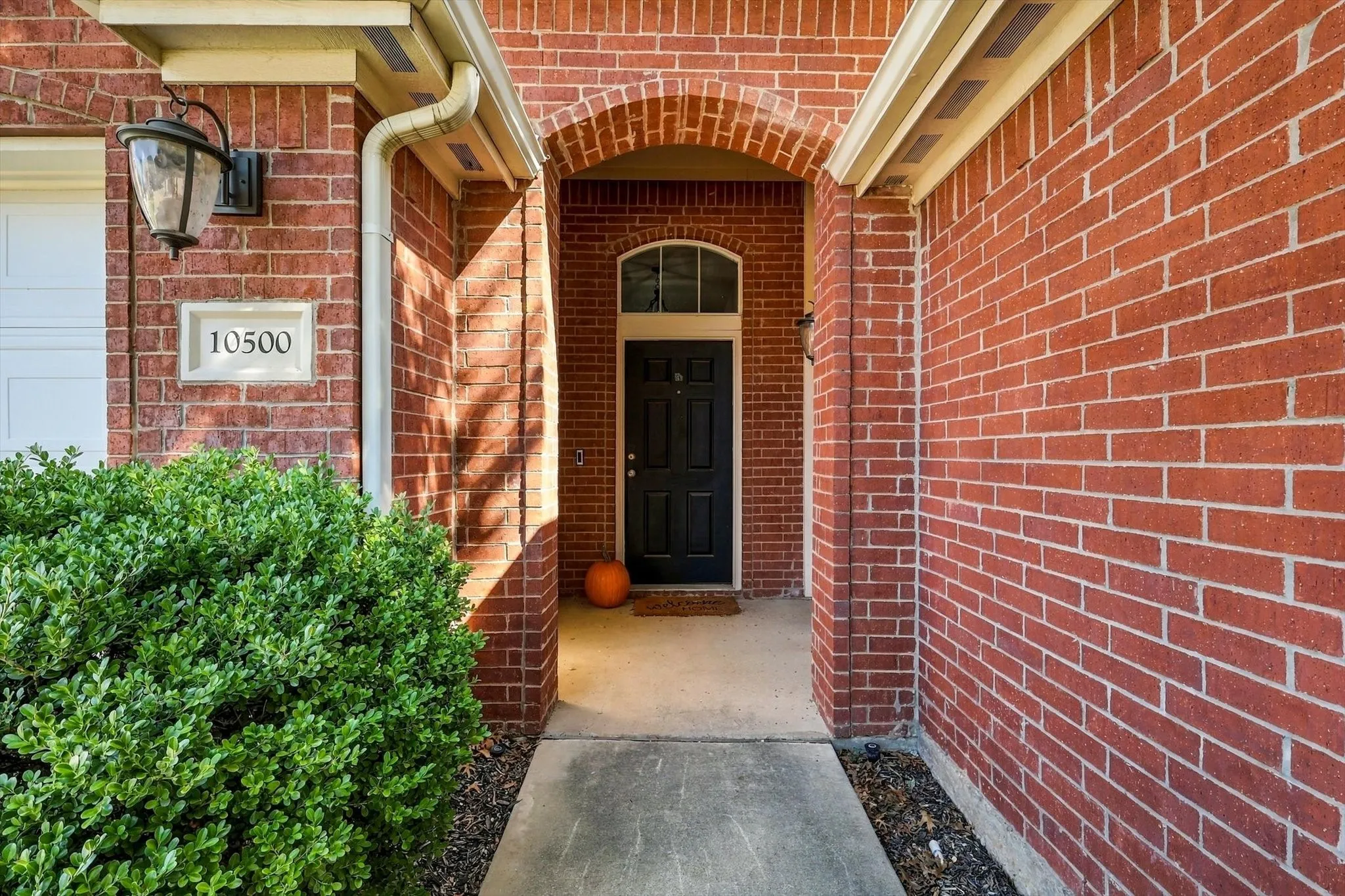Brick exterior with white mortar, arched entry, and a black front door with an arched transom window