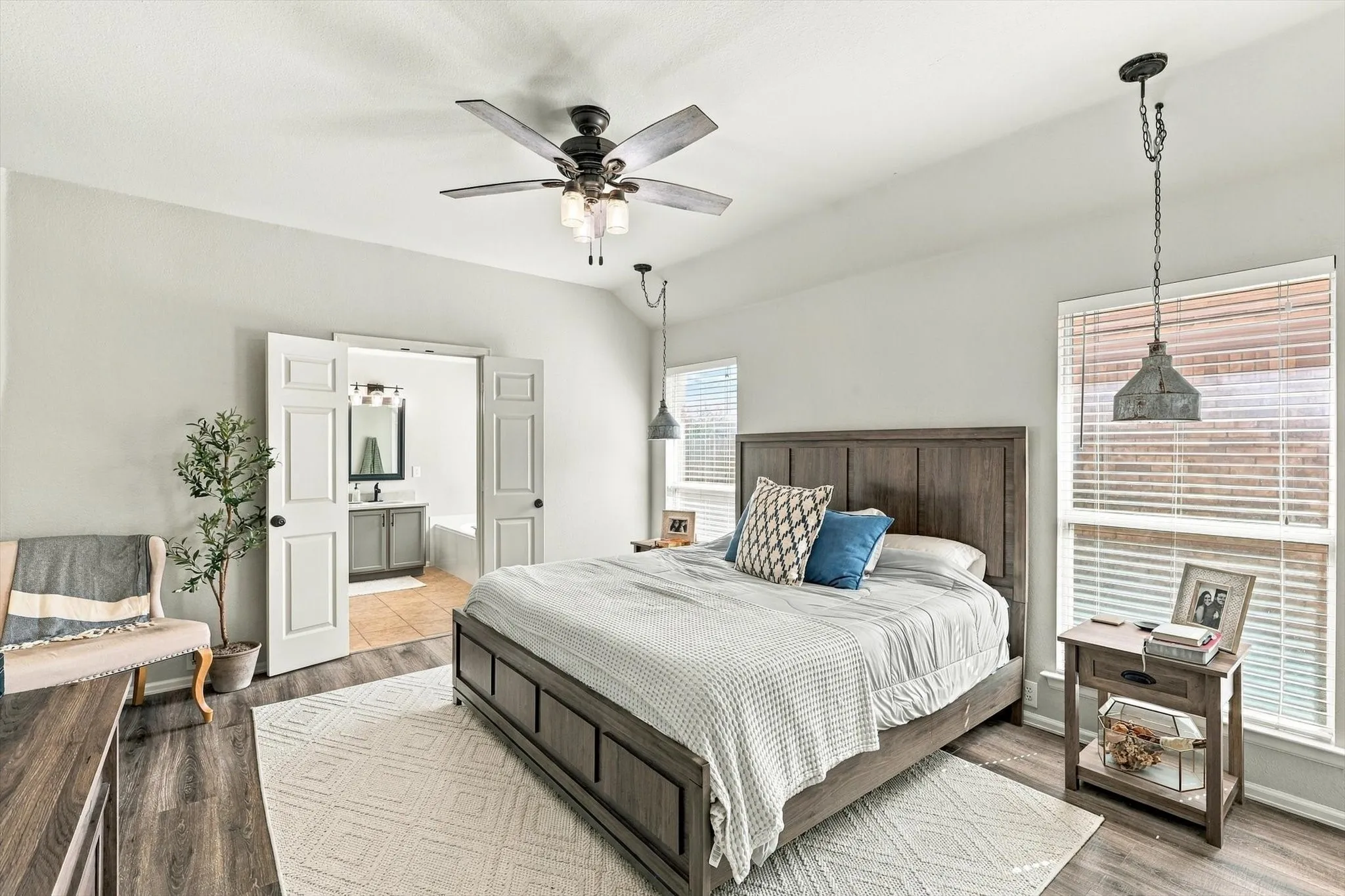 Vaulted ceiling, wood-finish flooring, ceiling fan with integrated lighting, double-door entry to bathroom, and window blinds