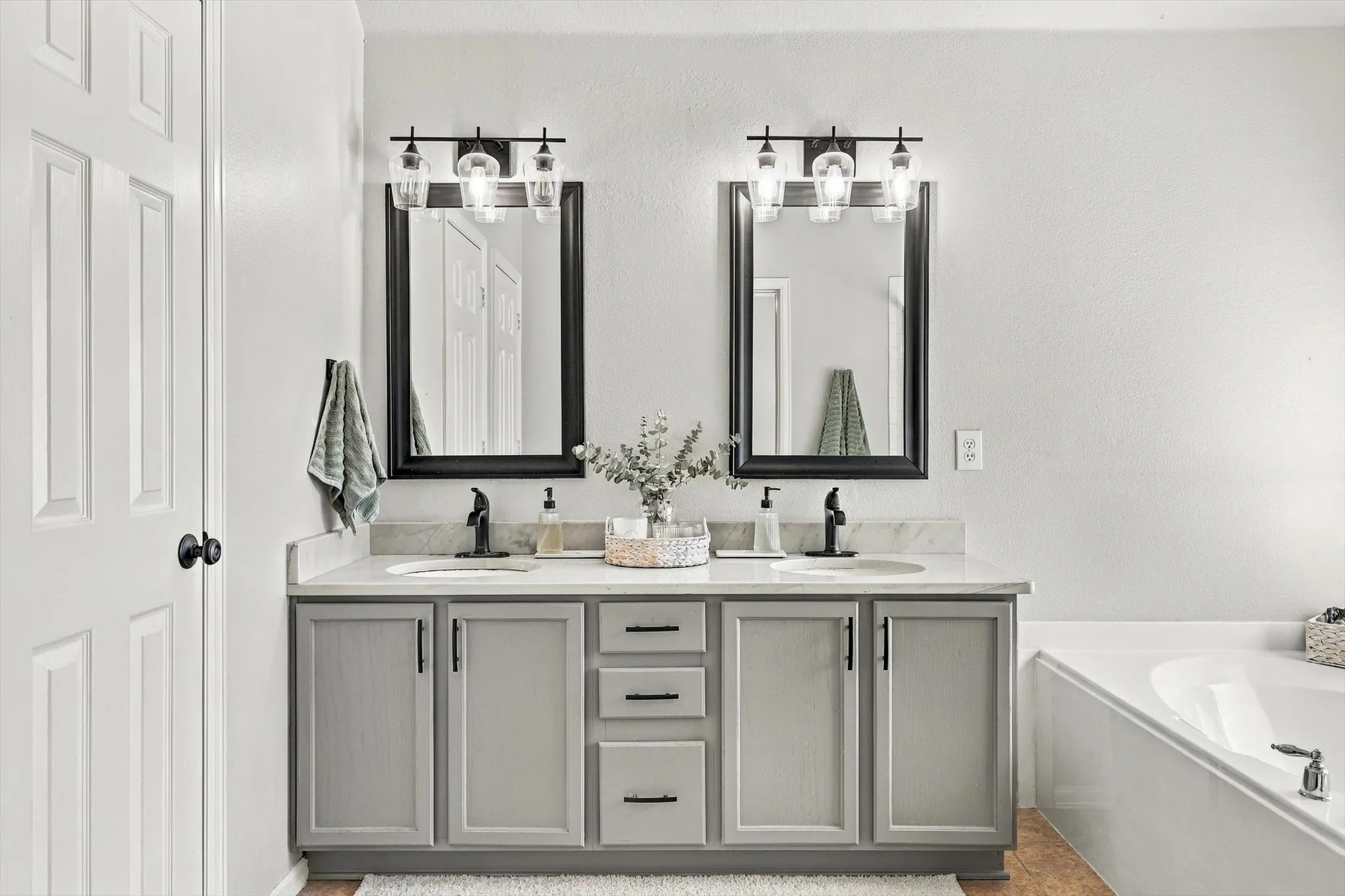 Dual vanity with undermount sinks, light-toned countertop, and matte black fixtures