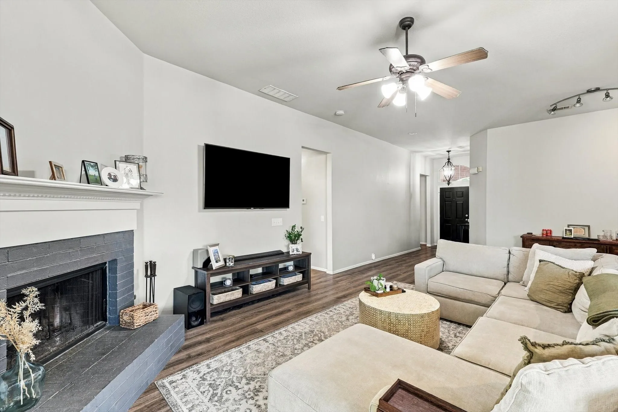 Living space featuring a fireplace with a gray brick surround, wood-finish flooring, a ceiling fan with integrated lighting, and recessed lighting