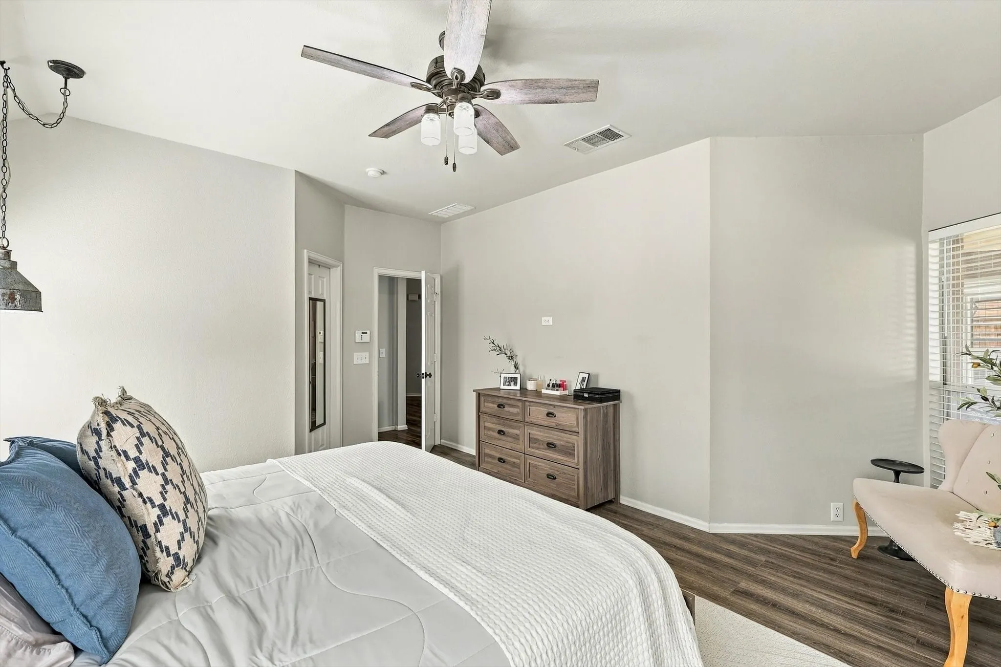 Wood-finish flooring with light-toned walls, ceiling fan with light fixture, and a built-in window with blinds