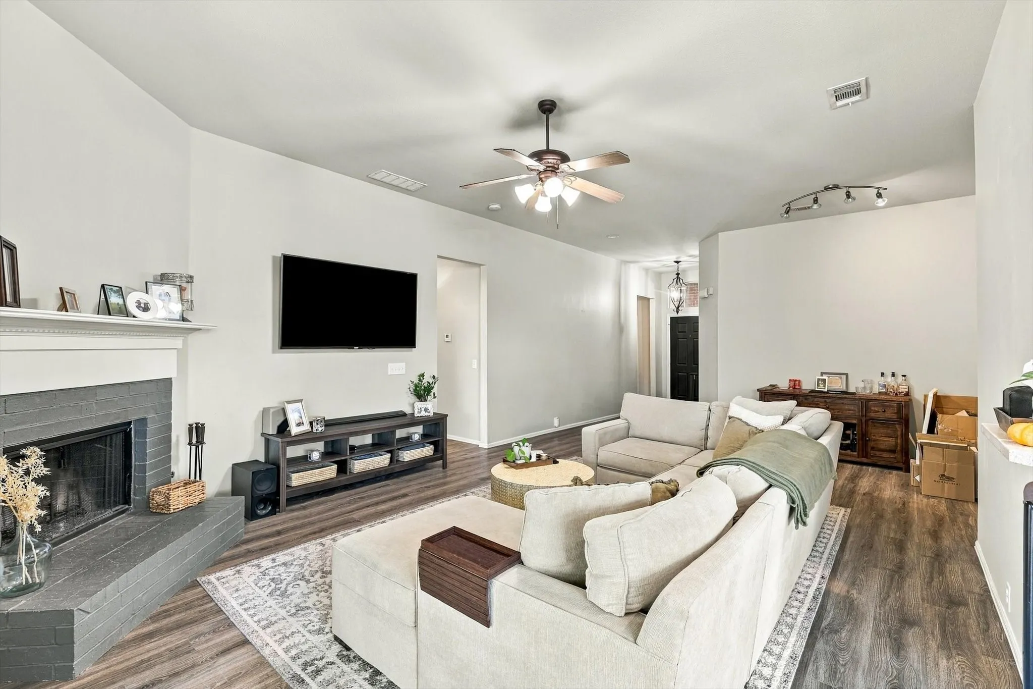 Vaulted ceiling with a ceiling fan, fireplace with a mantel, wood-finish flooring, and recessed lighting