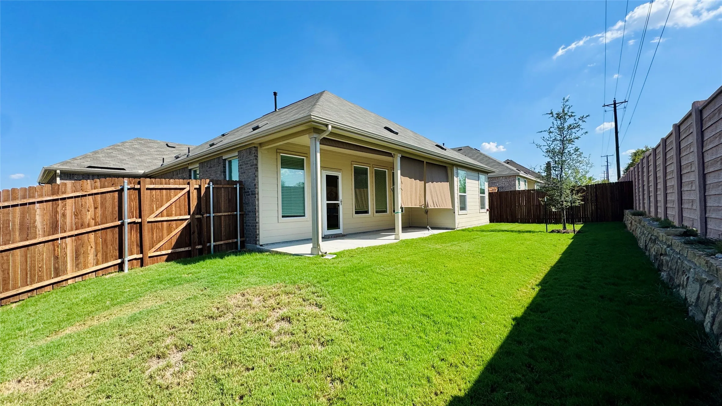 Expansive backyard with a covered patio, manicured lawn, and privacy fencing