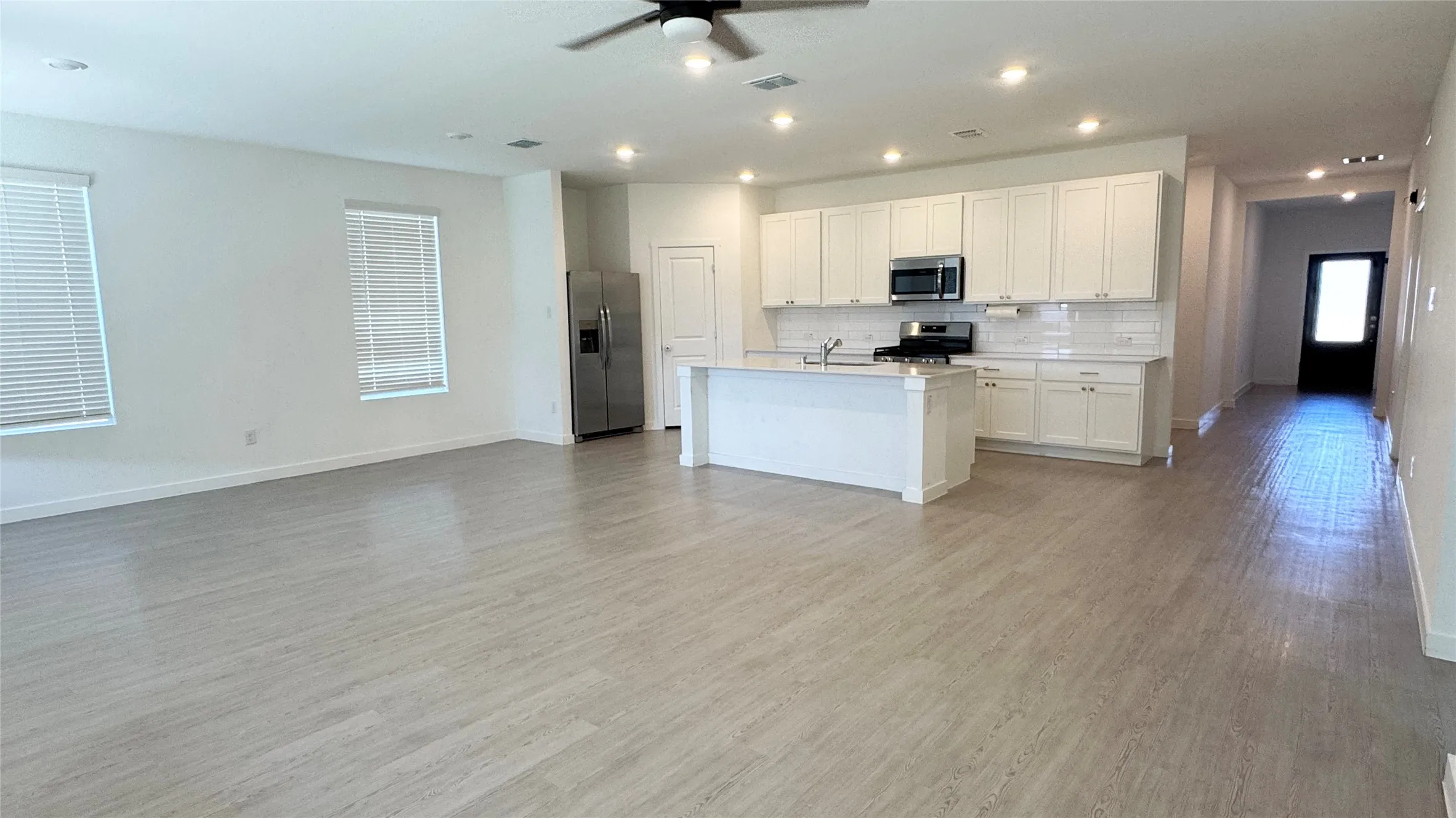 Open-concept living area with wood-finish flooring, recessed lighting, and a ceiling fan