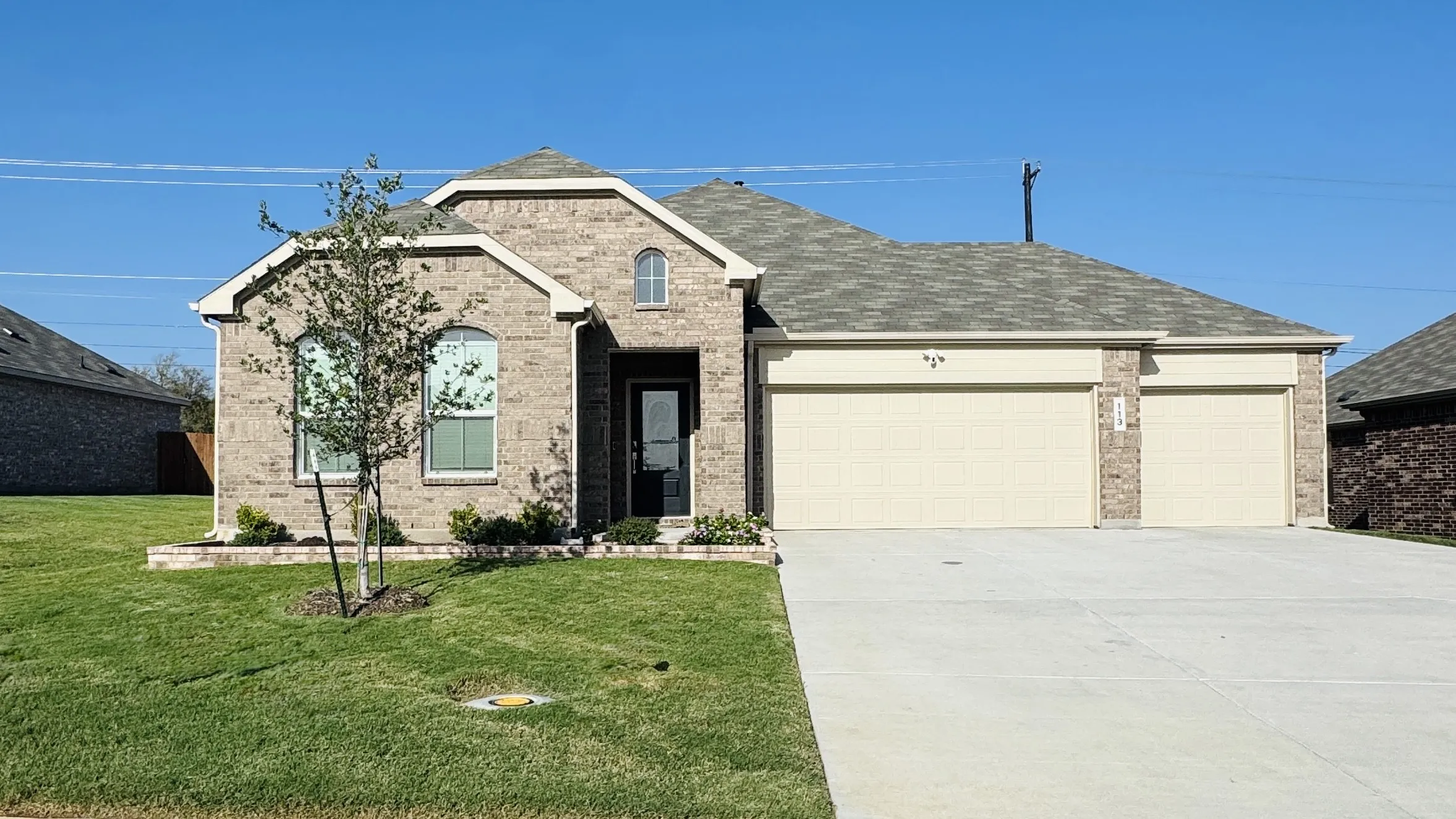 Brick exterior with arched windows, a covered entry, and a 3 car garage