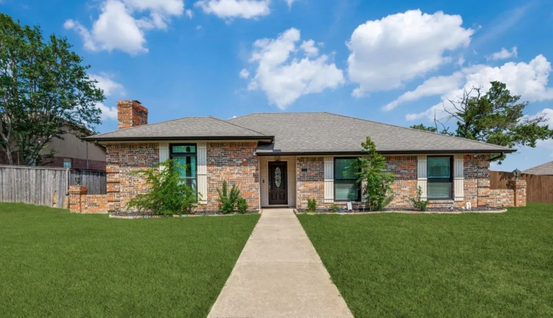 Welcoming single-story brick home with a spacious front lawn and inviting entryway.