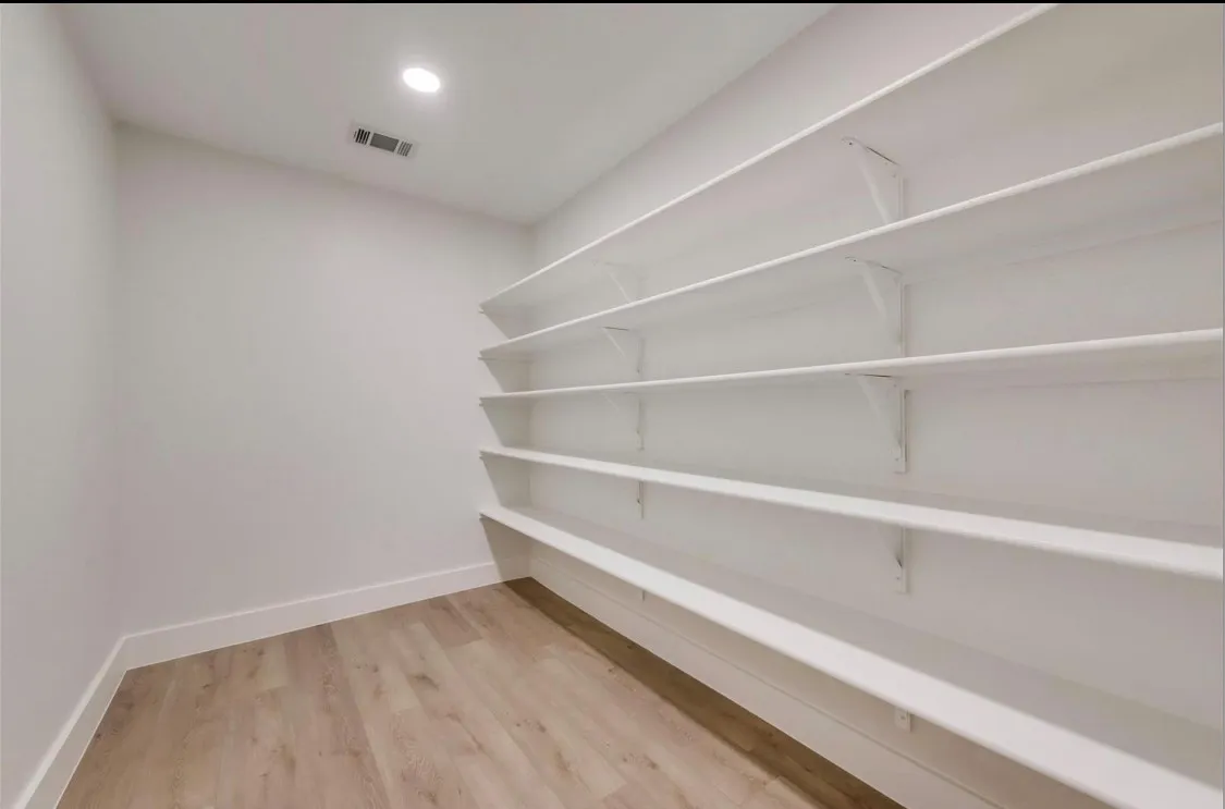 Generously sized walk-in pantry with extensive built-in shelving for storage and organization.