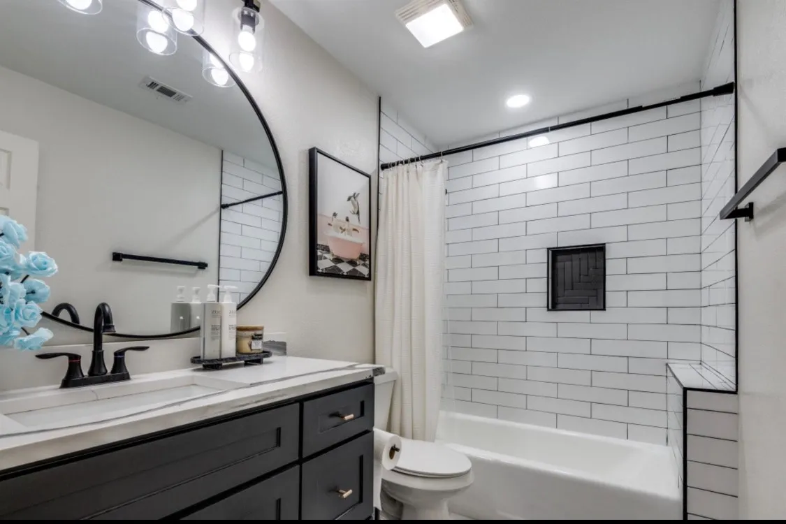 Updated secondary bathroom featuring marble-look flooring, modern vanity, and tiled tub surround.