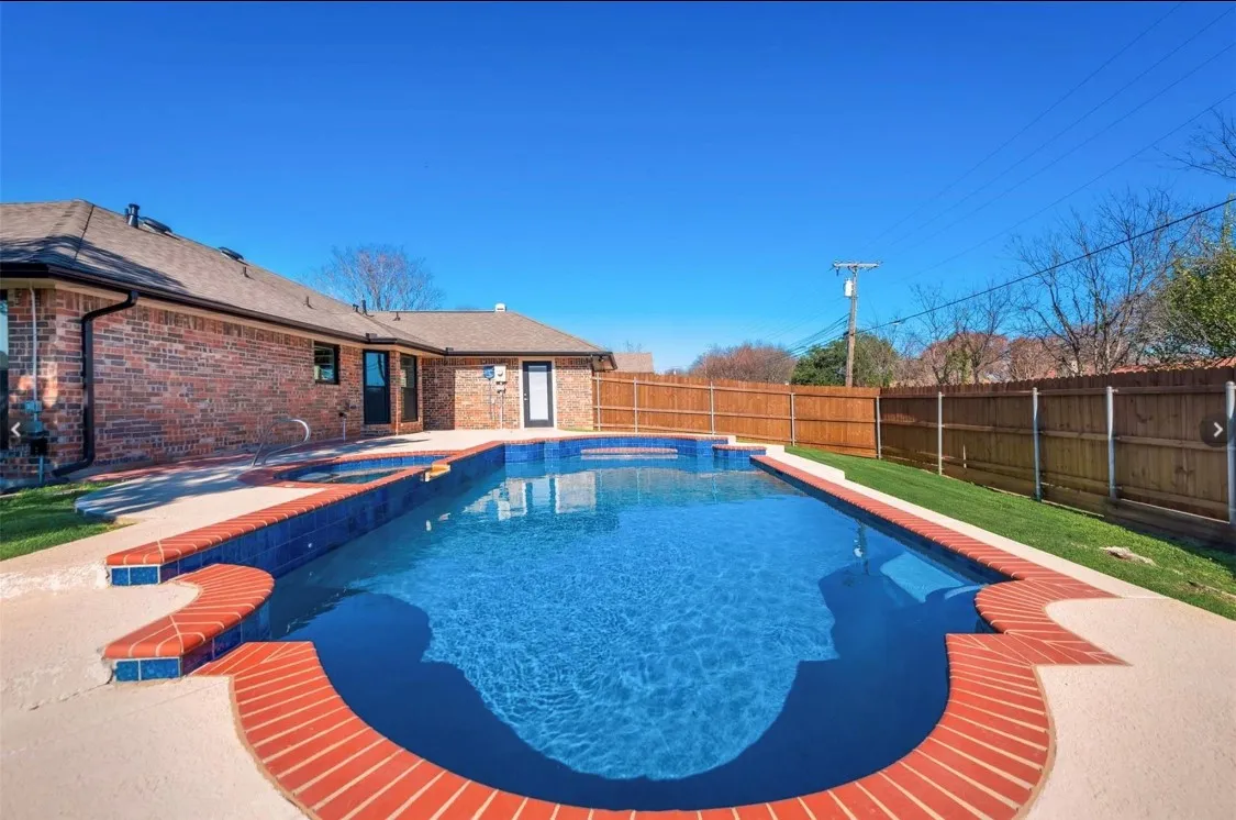 Additional view of the backyard oasis featuring the swimming pool, brick patio, and fenced yard.