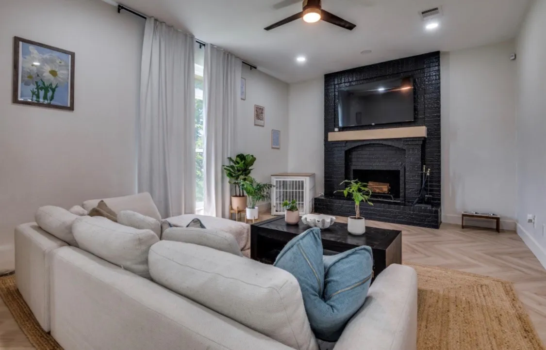 Black brick fireplace with wood mantel, herringbone wood-finish flooring, recessed lighting, and ceiling fan