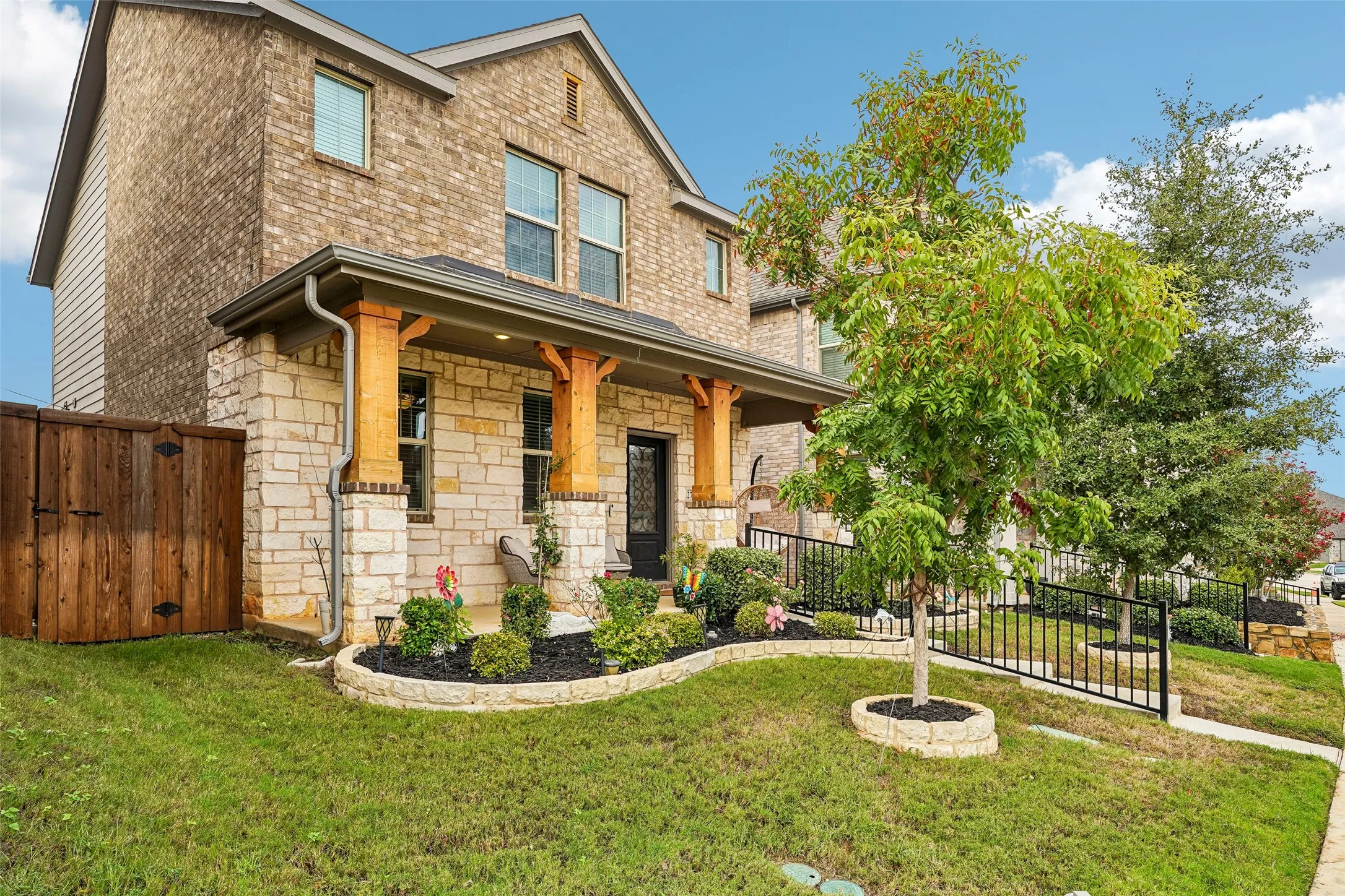 Brick and stone facade with a covered porch featuring wood columns