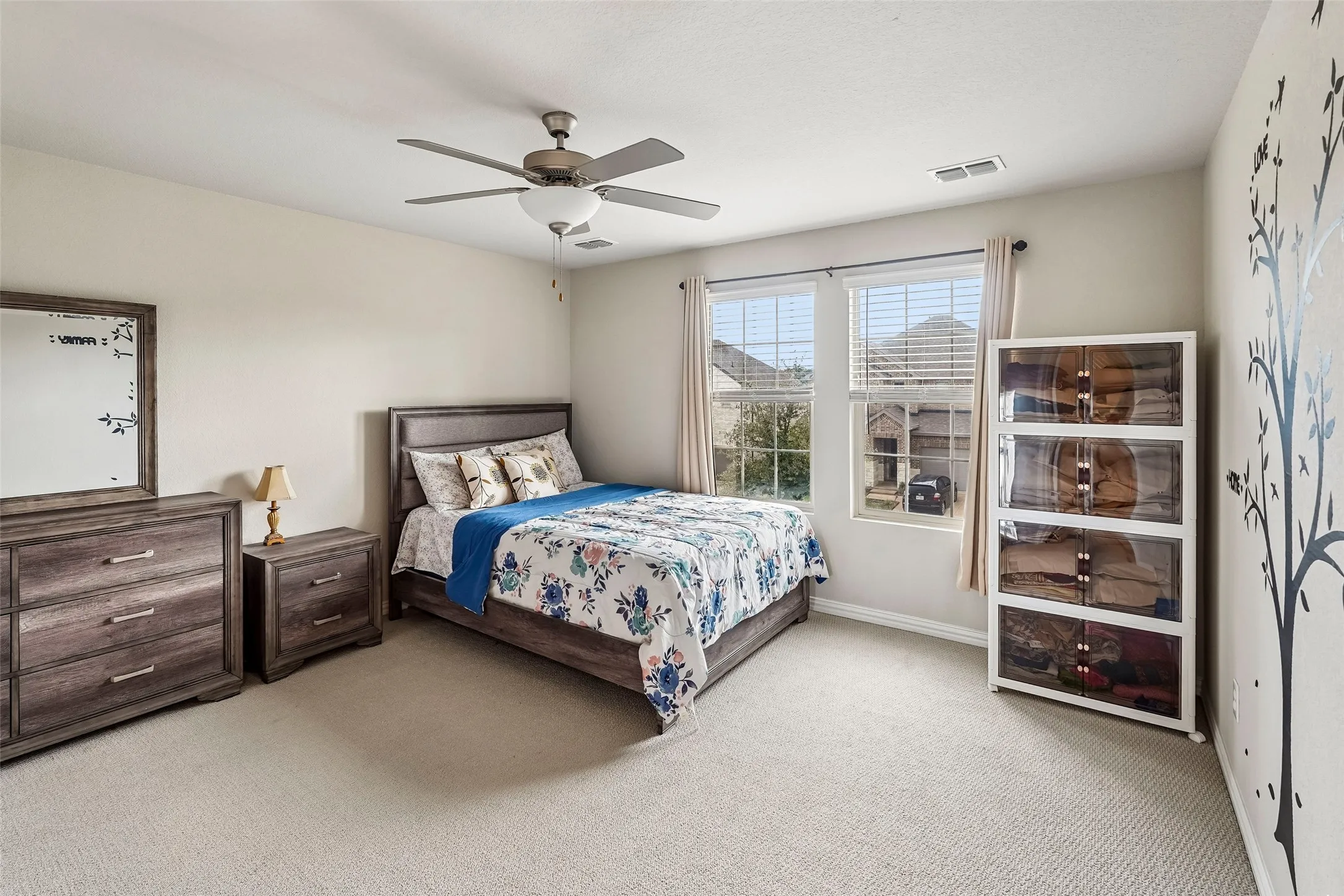 Carpeted bedroom featuring a ceiling fan with integrated lighting, two windows, and neutral wall tones