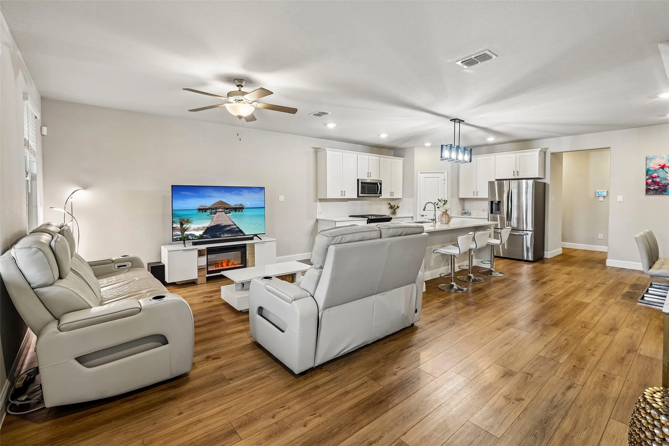 Open-concept living space featuring wood-finish flooring, a ceiling fan, and recessed lighting