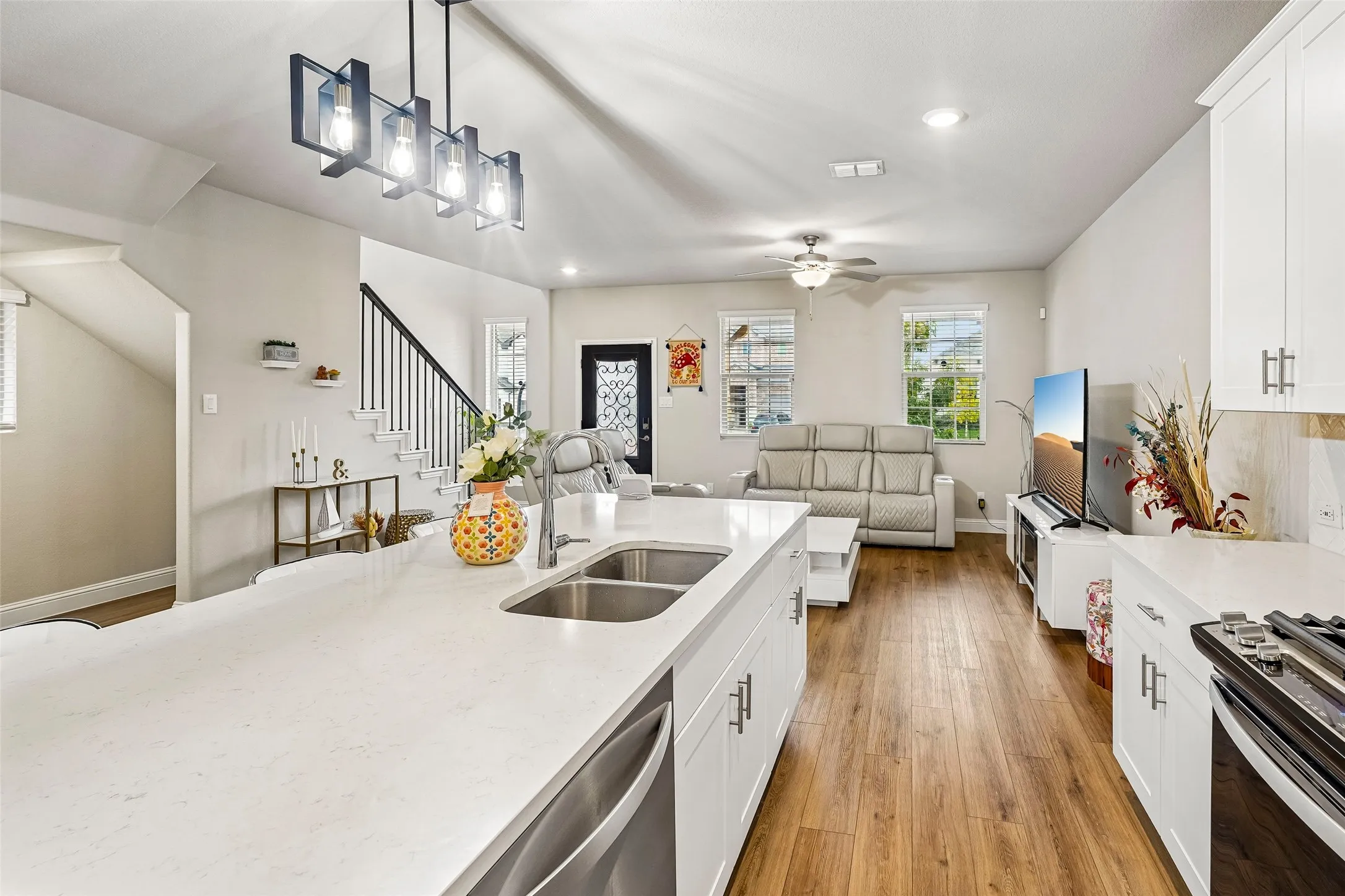 Kitchen island with an undermount double-basin sink, crisp white cabinetry, and stainless steel appliances