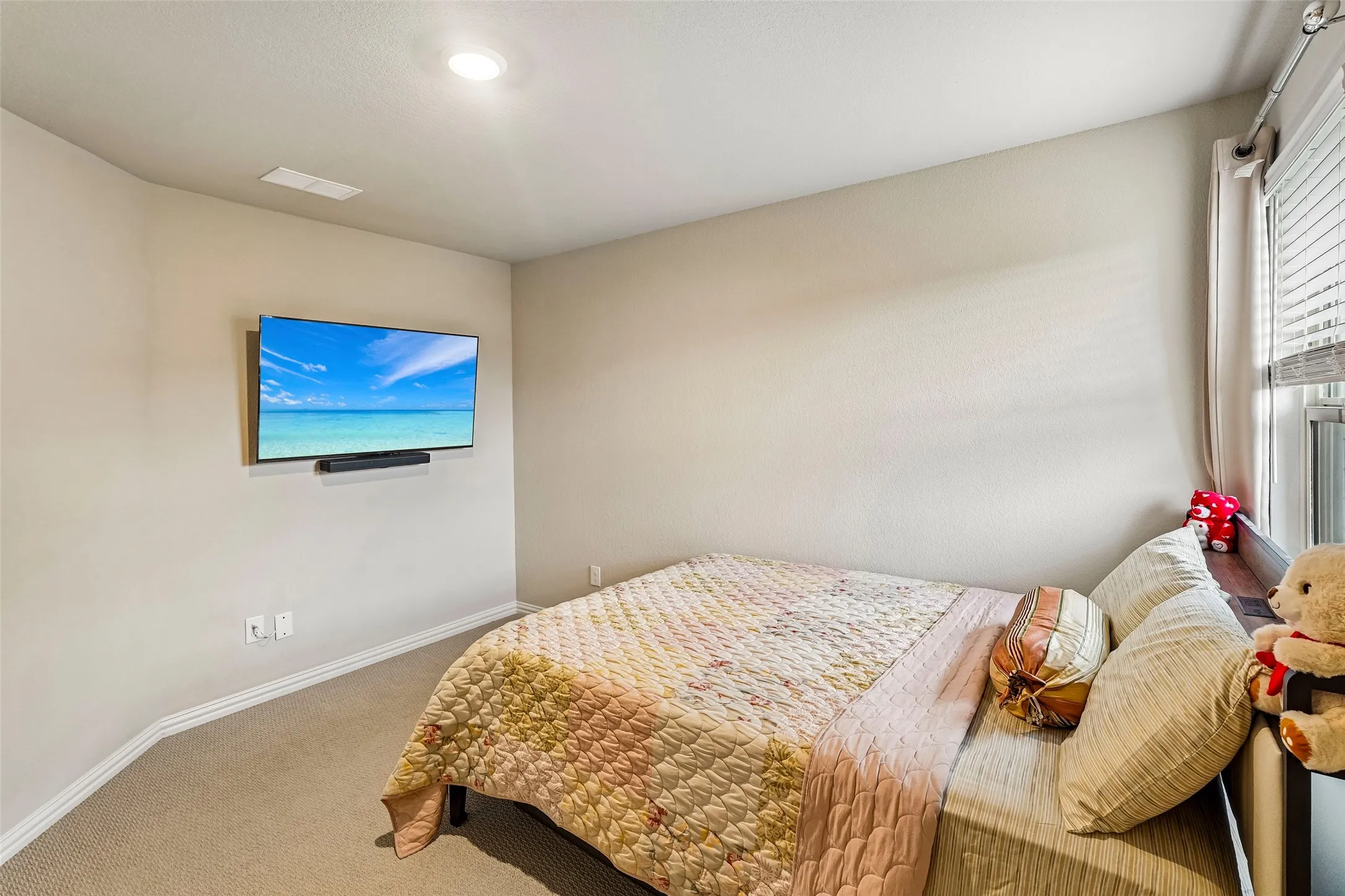 Recessed lighting, wall-mounted television, window with blinds, carpeted flooring, and neutral wall tones