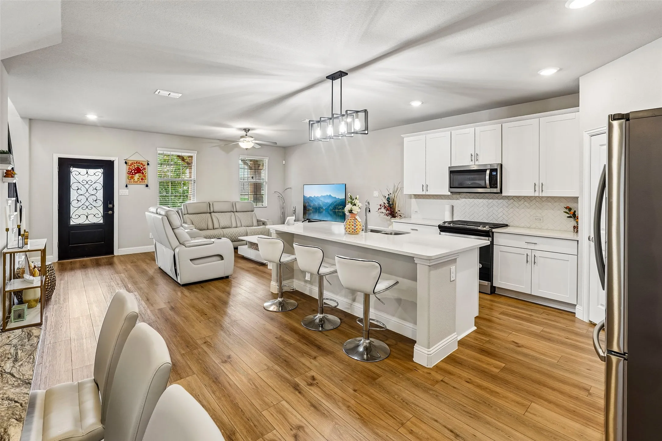 Open-concept living space with wood-finish flooring, recessed lighting, and a kitchen island featuring a breakfast bar
