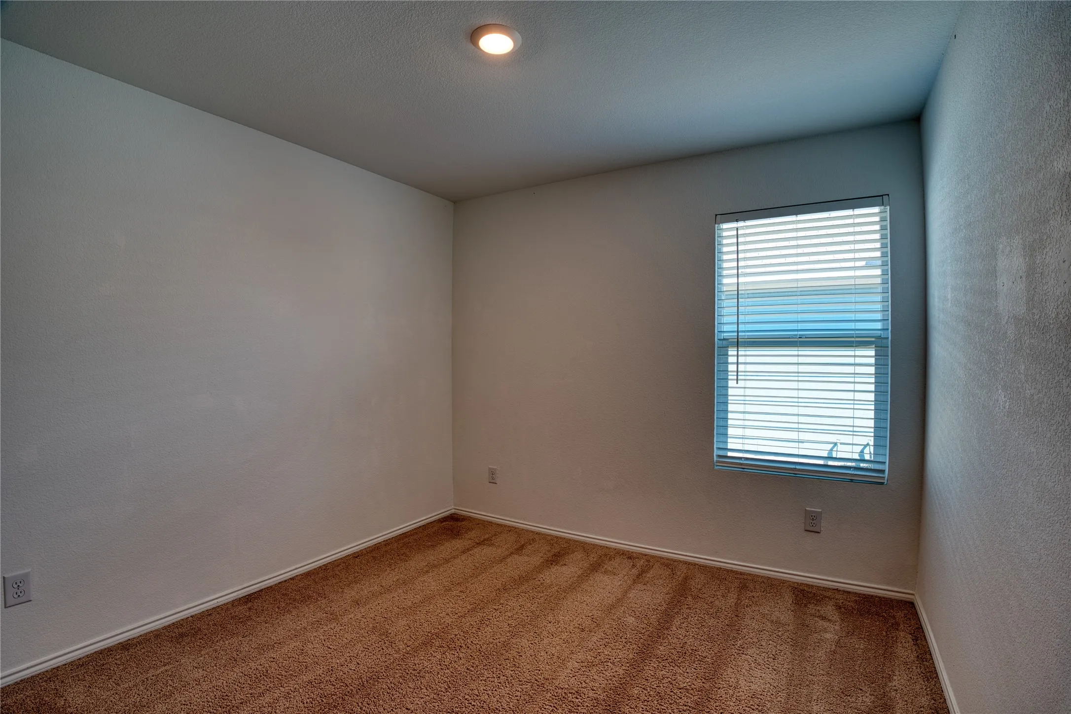 Recessed ceiling lighting, textured walls, window with horizontal blinds, and carpeting