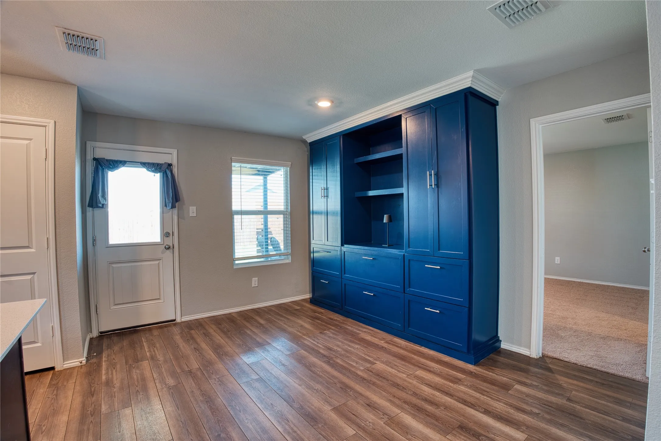 Wood-finish flooring throughout, complemented by a prominent built-in storage unit with open shelving and closed cabinetry