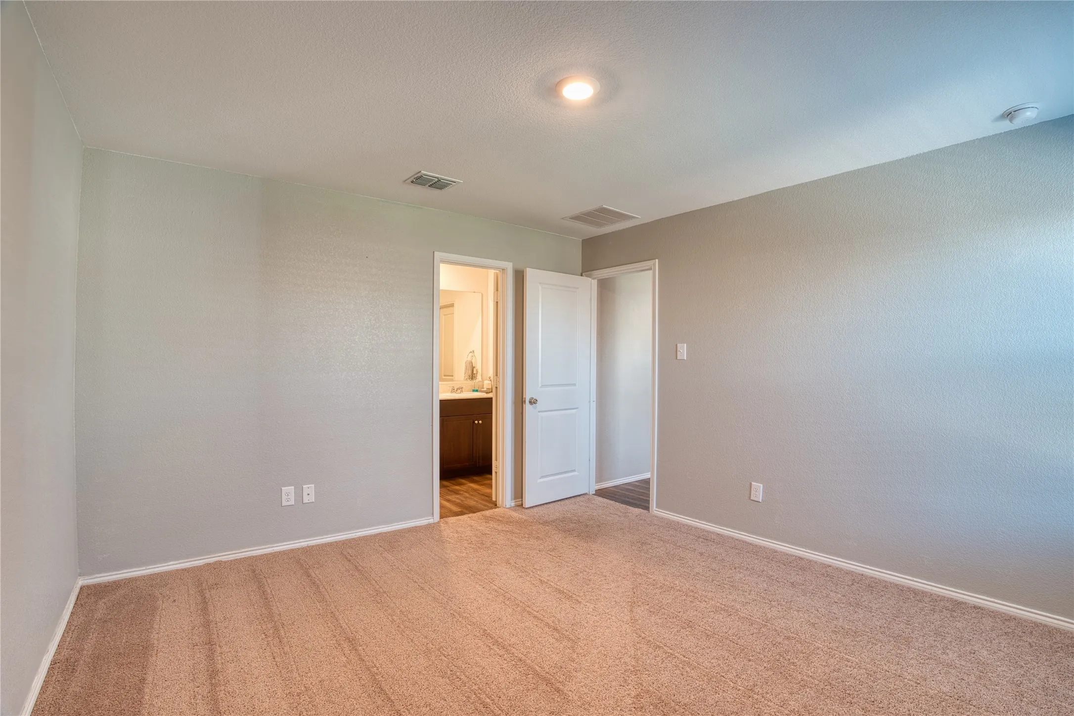 Recessed ceiling lighting, textured wall finish, and a carpeted floor