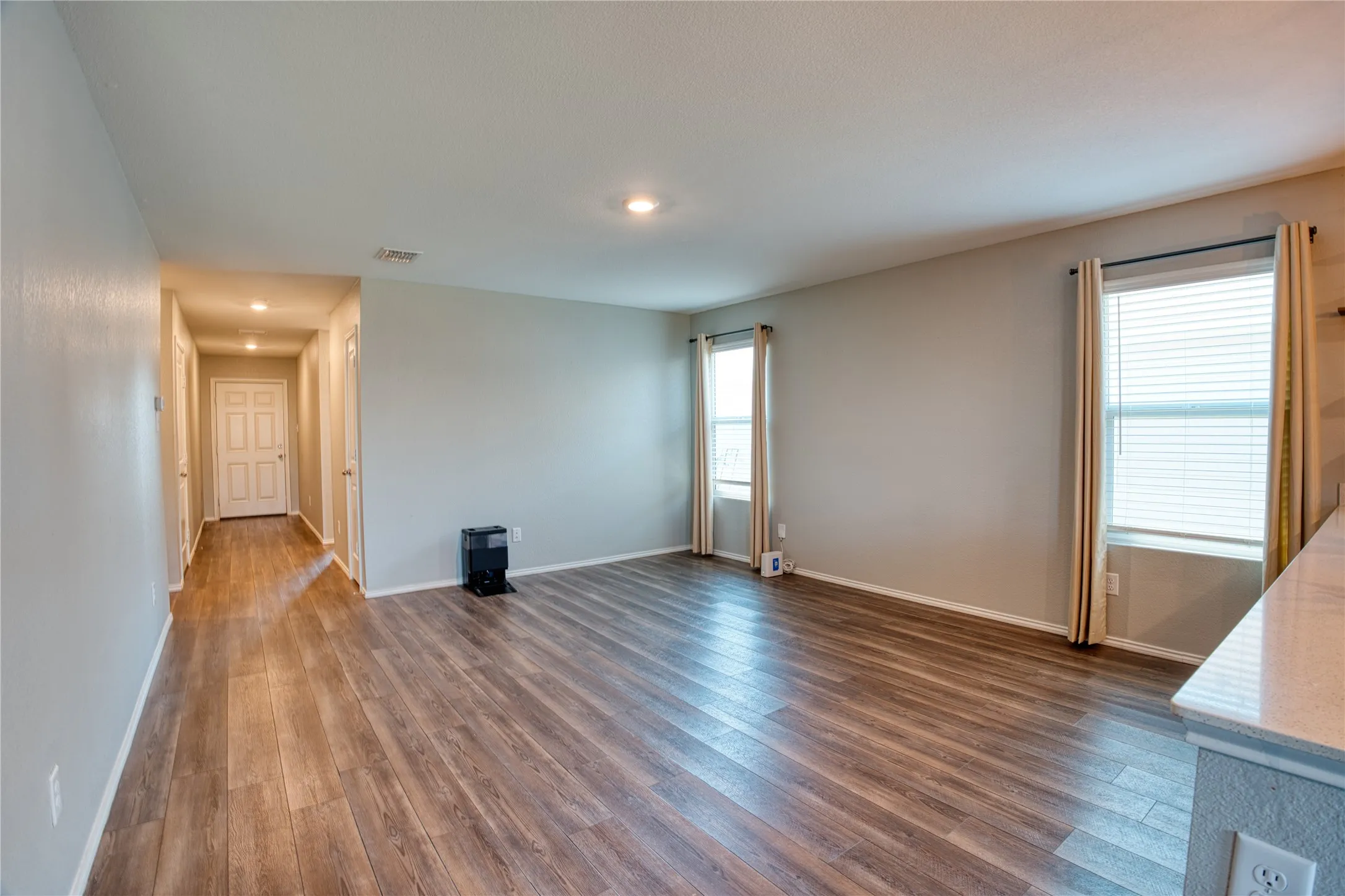 Wood-finish flooring throughout, recessed lighting, and multiple windows with blinds