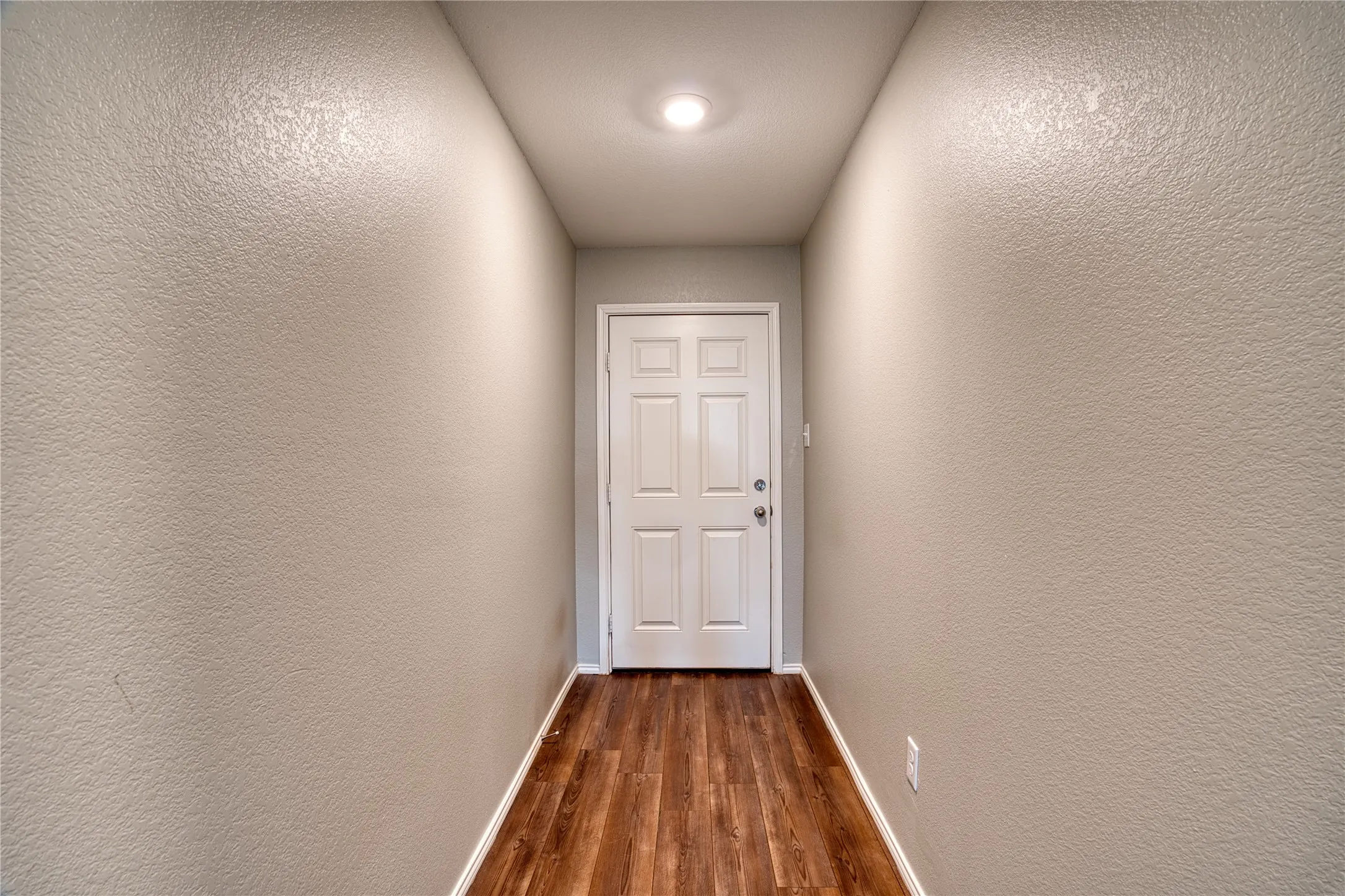 Entryway featuring wood-finish flooring, recessed lighting, and a paneled door