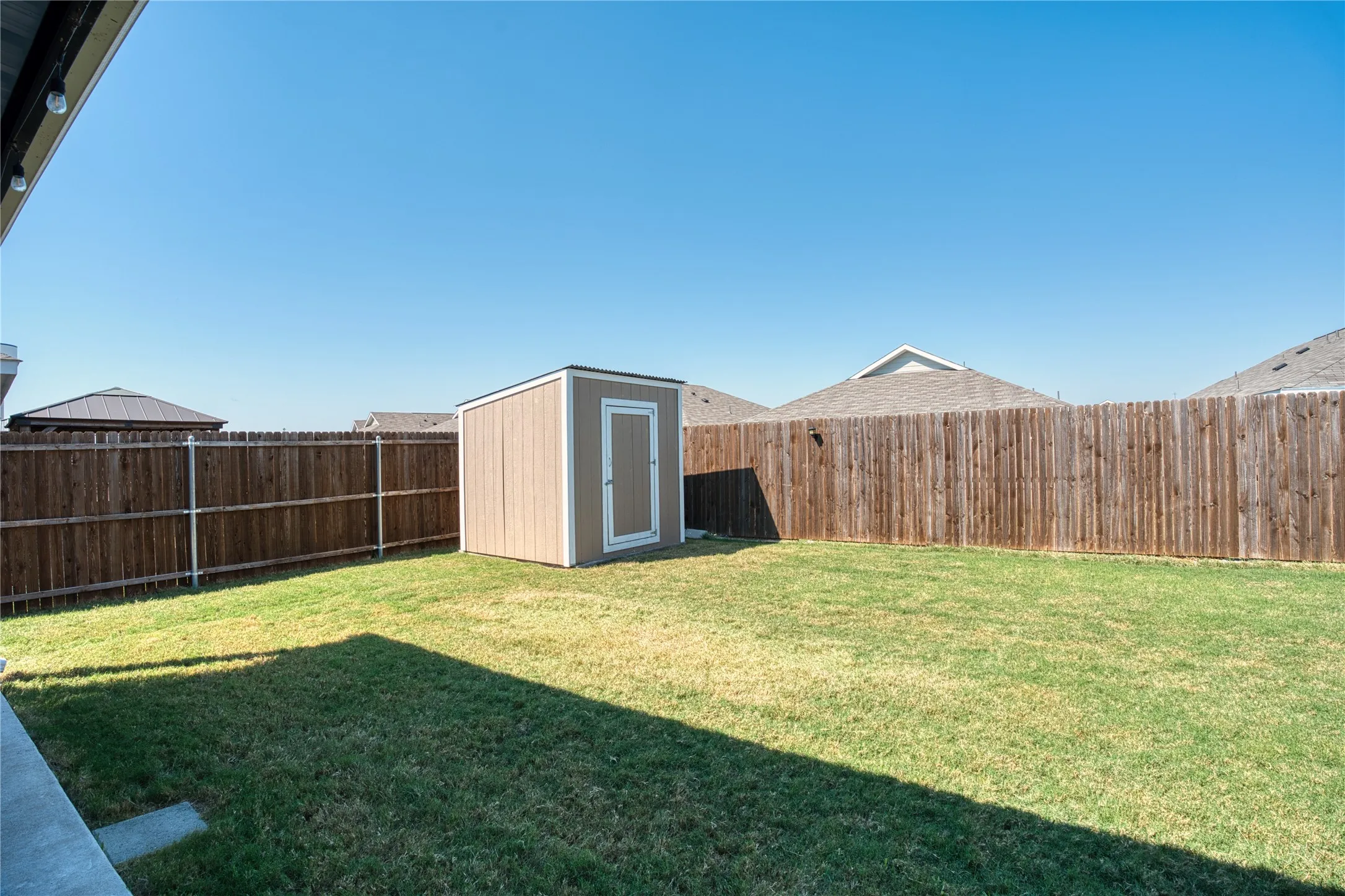 Spacious backyard featuring a storage shed, wood privacy fencing, and a manicured lawn