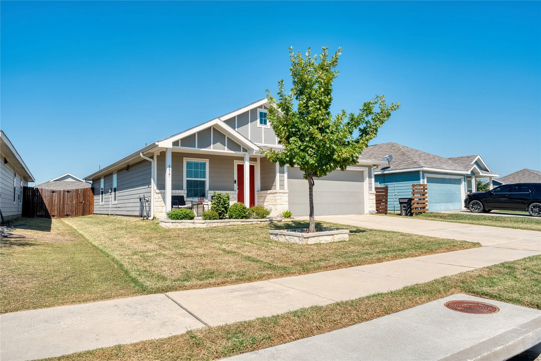 Single-story residence featuring a gray exterior with white trim, a red front door, and an attached two-car garage