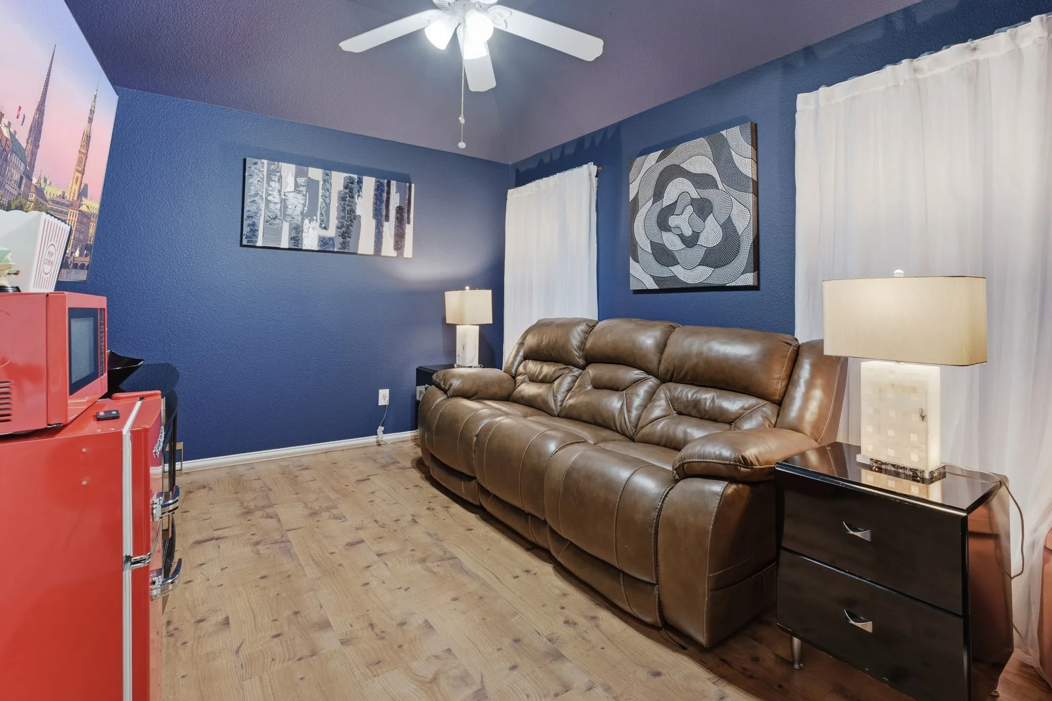 Wood-finish flooring with a ceiling fan light fixture and dual window openings