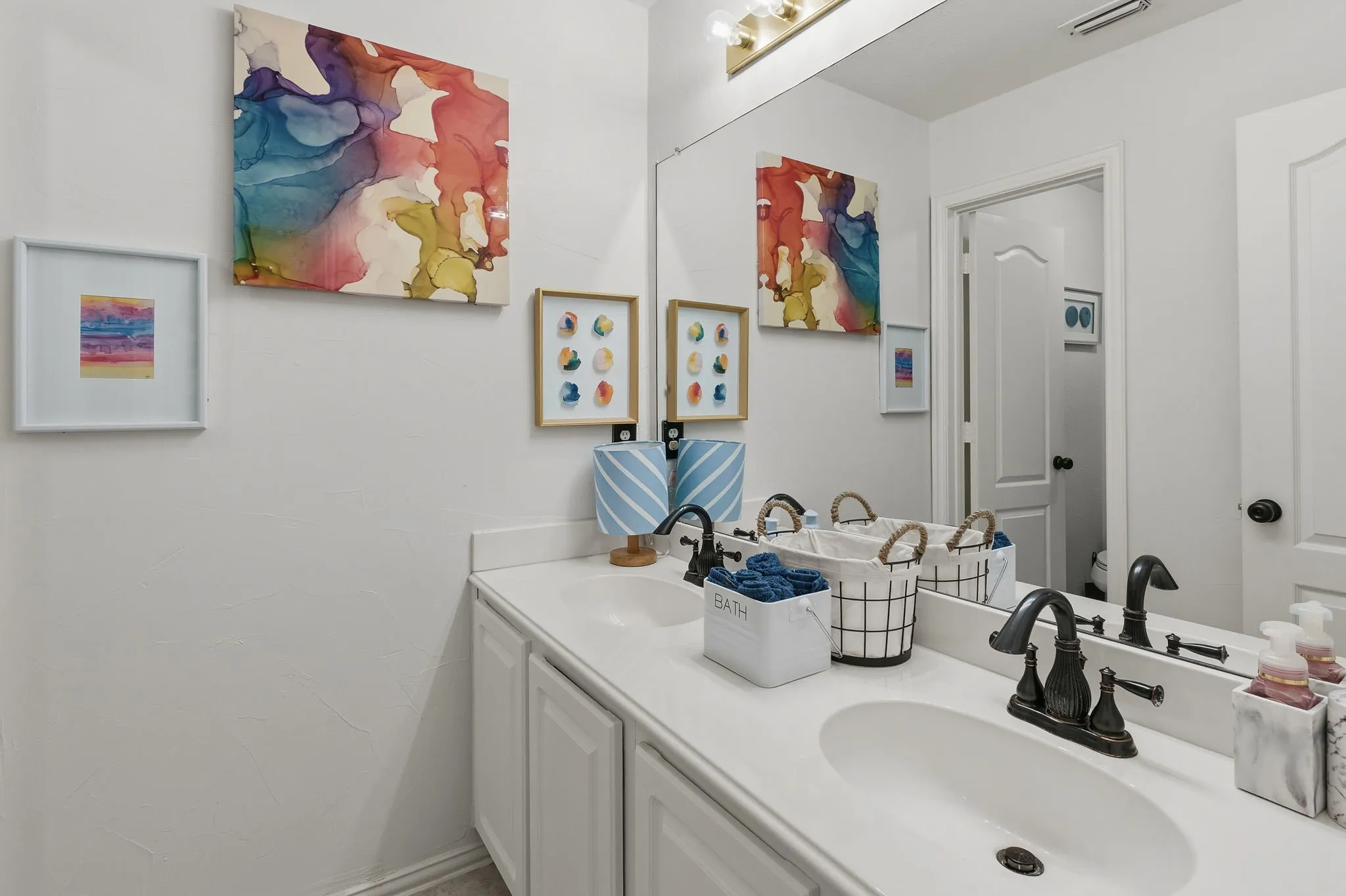 Double vanity with white cabinetry, solid surface countertop, dual undermount sinks, and oil-rubbed bronze fixtures