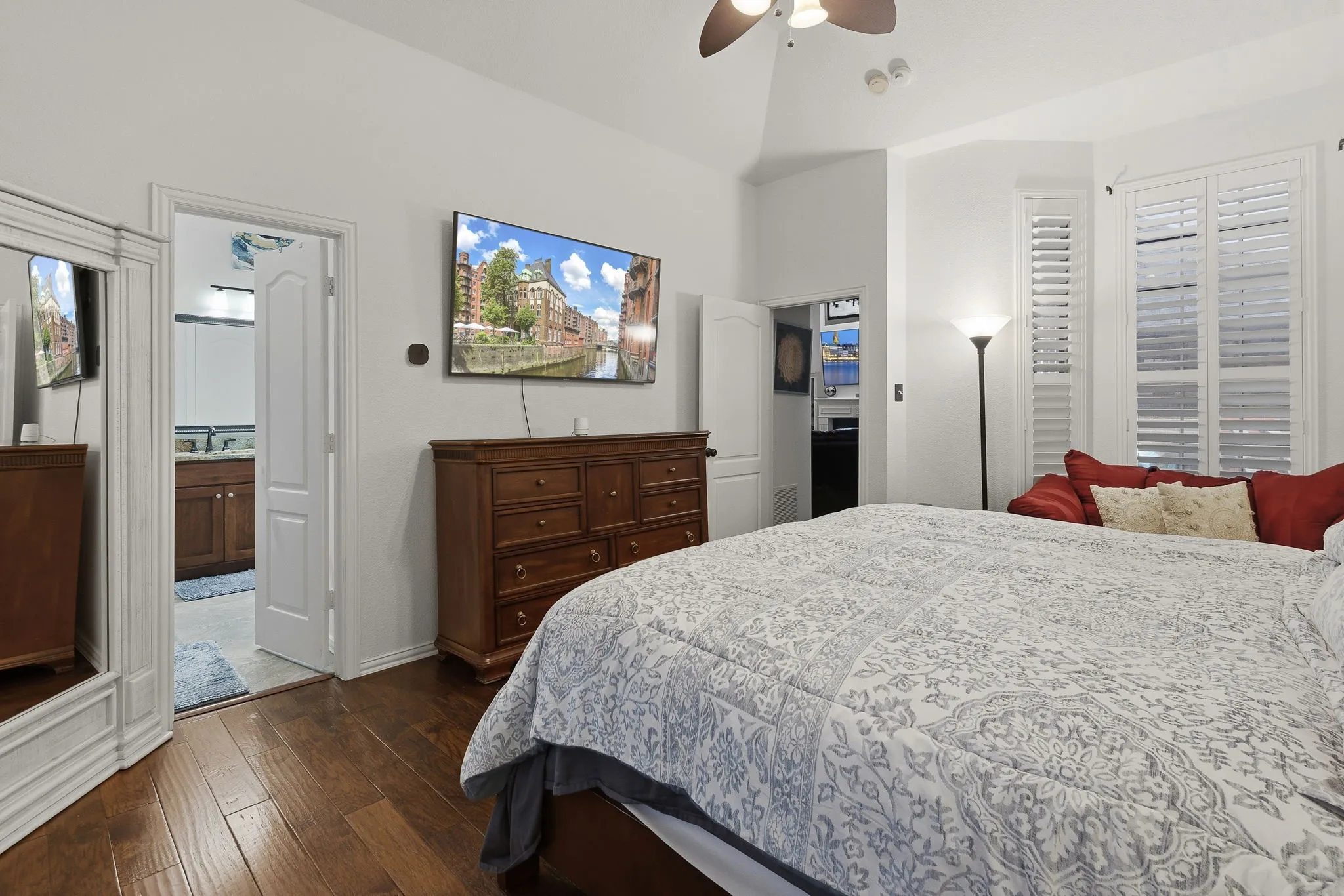 Vaulted ceiling, wood-finish flooring, plantation shutters, ceiling fan, and an en-suite bathroom