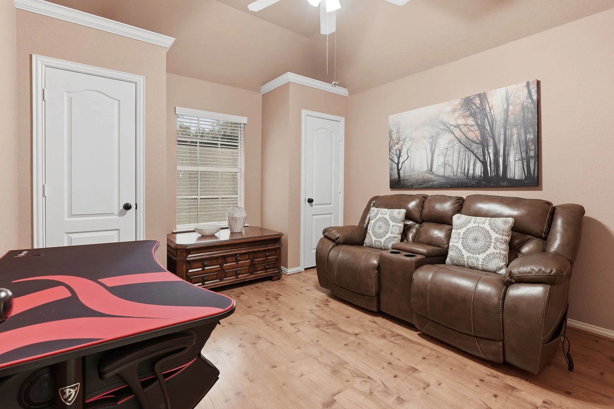 Vaulted ceiling, wood-finish flooring, white paneled doors, crown molding, and a ceiling fan