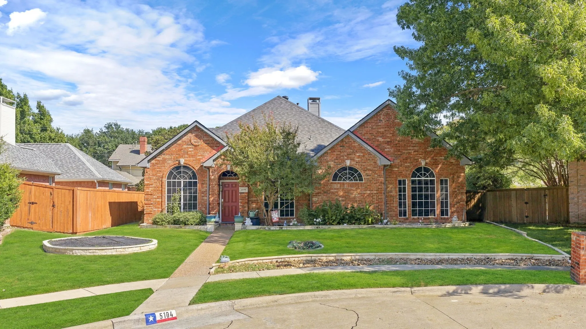 Brick exterior with an arched entry, prominent arched windows, and a manicured lawn