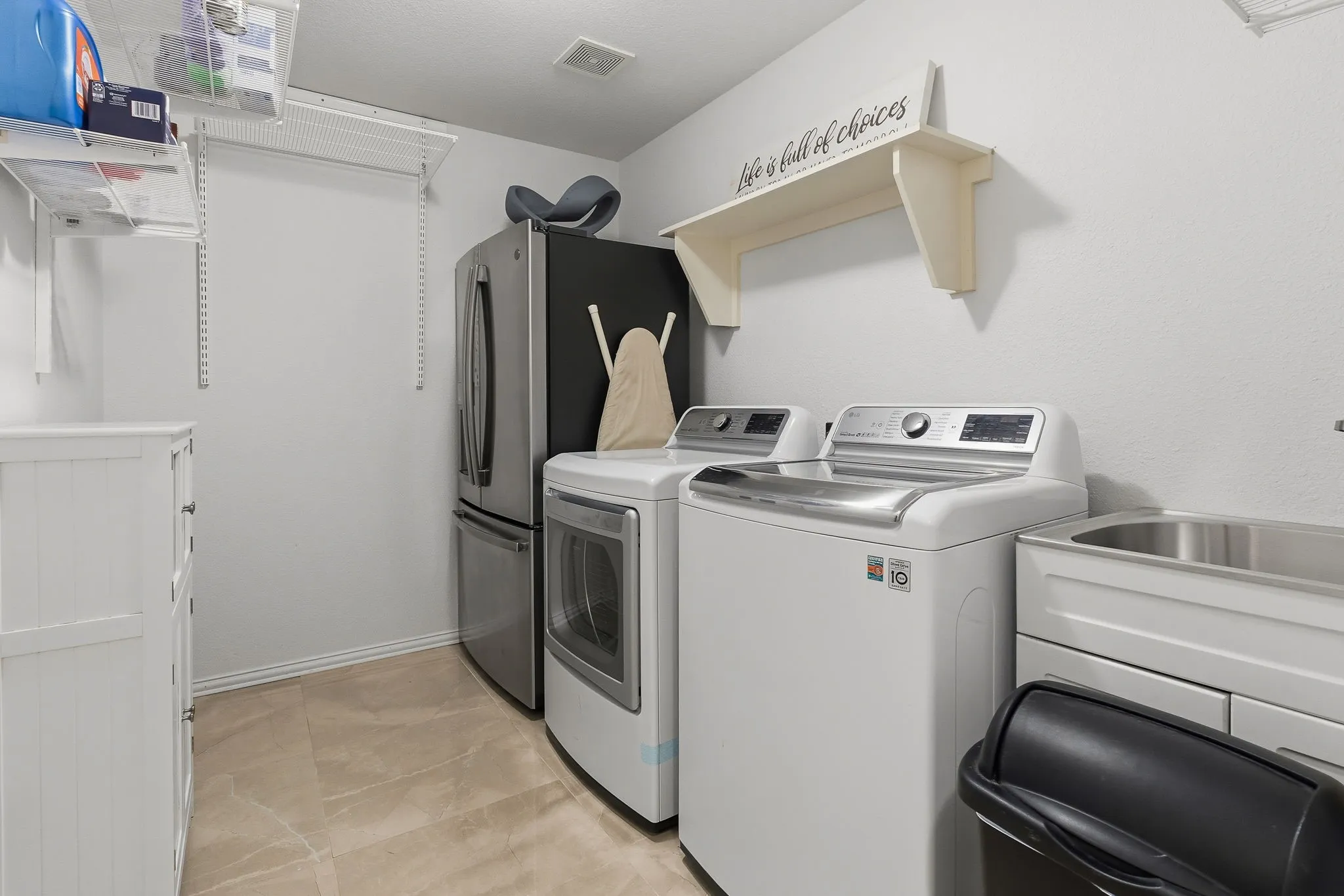 Utility room featuring a built-in stainless steel sink, tiled flooring, and wire shelving