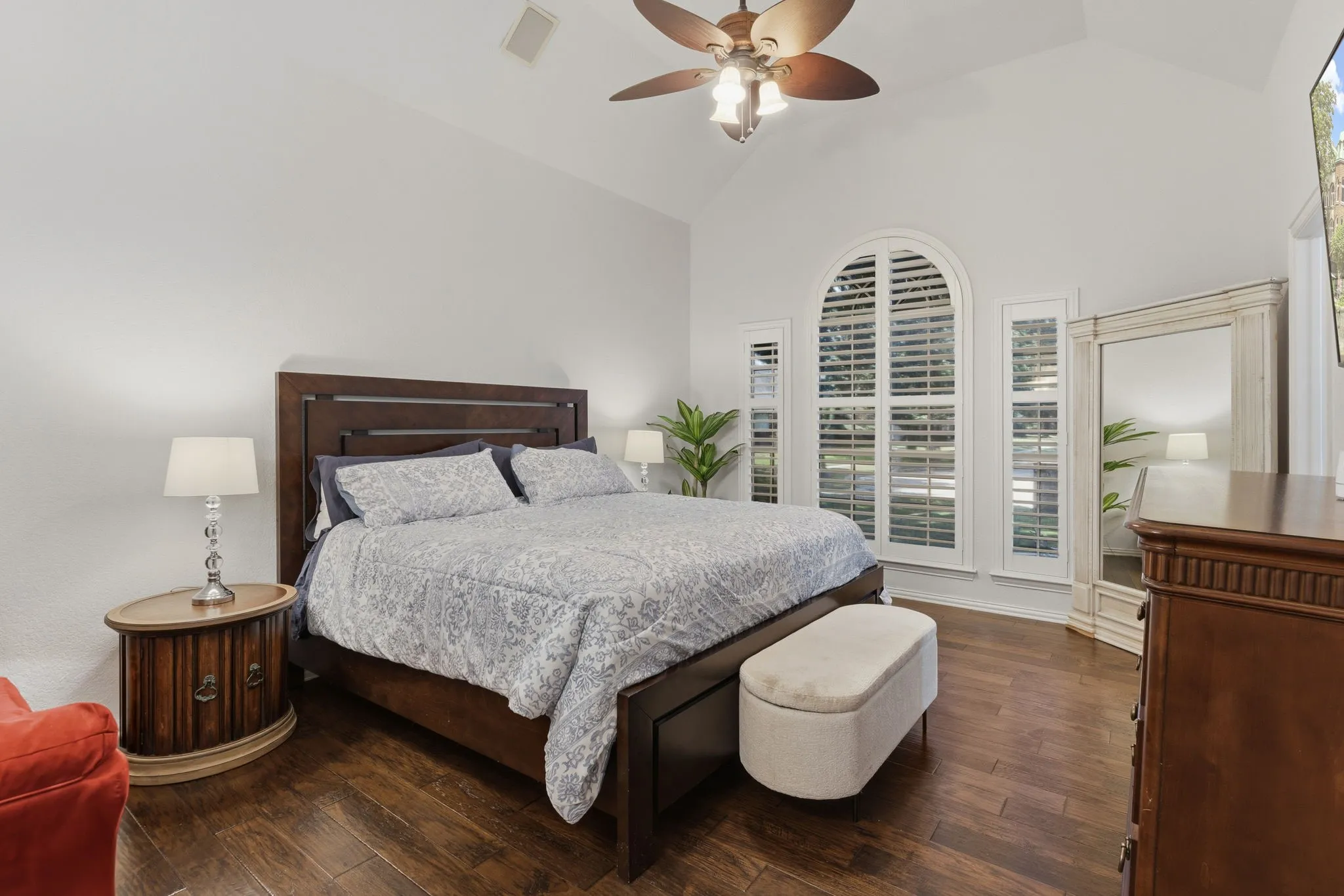 Vaulted ceiling with a ceiling fan, hardwood flooring, arched window with plantation shutters, and recessed lighting