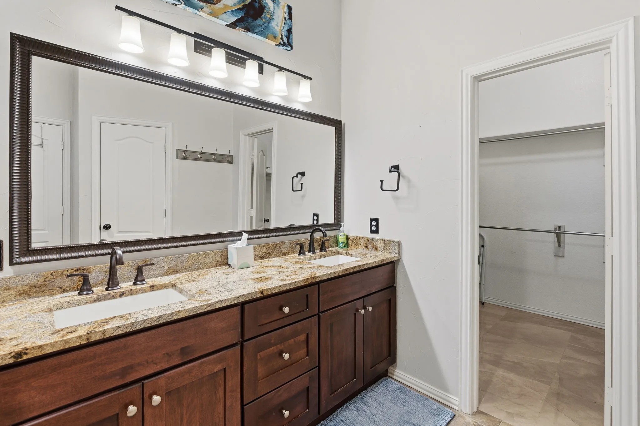 Dual vanity with undermount sinks, granite countertop, dark wood-finish cabinetry, and oil-rubbed bronze fixtures