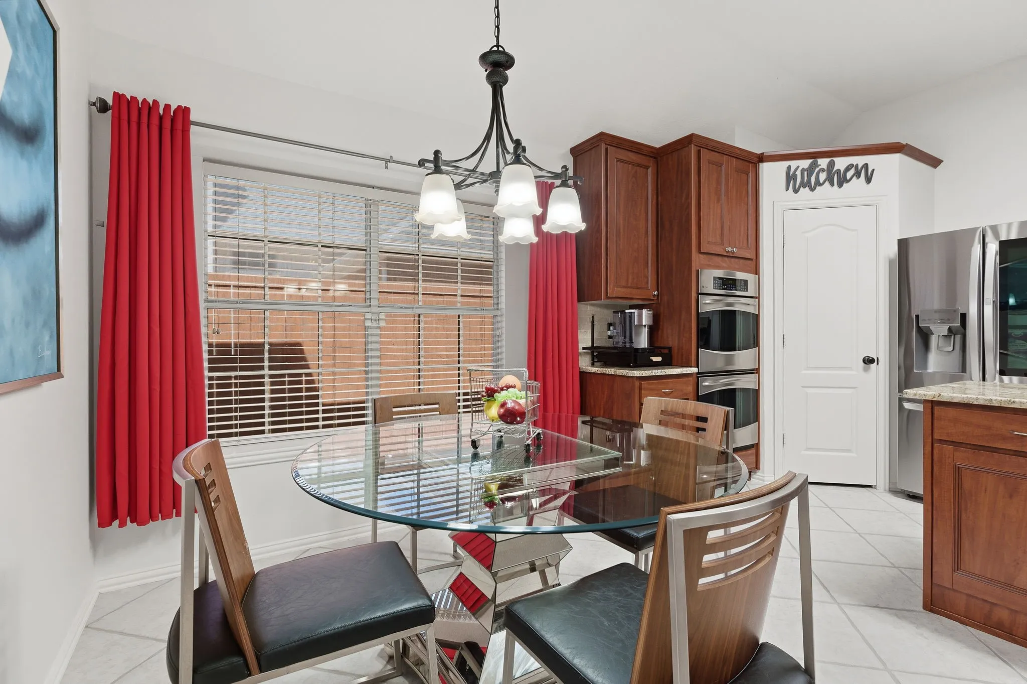 Warm wood cabinetry with stone countertops, integrated double ovens, and stainless steel refrigerator