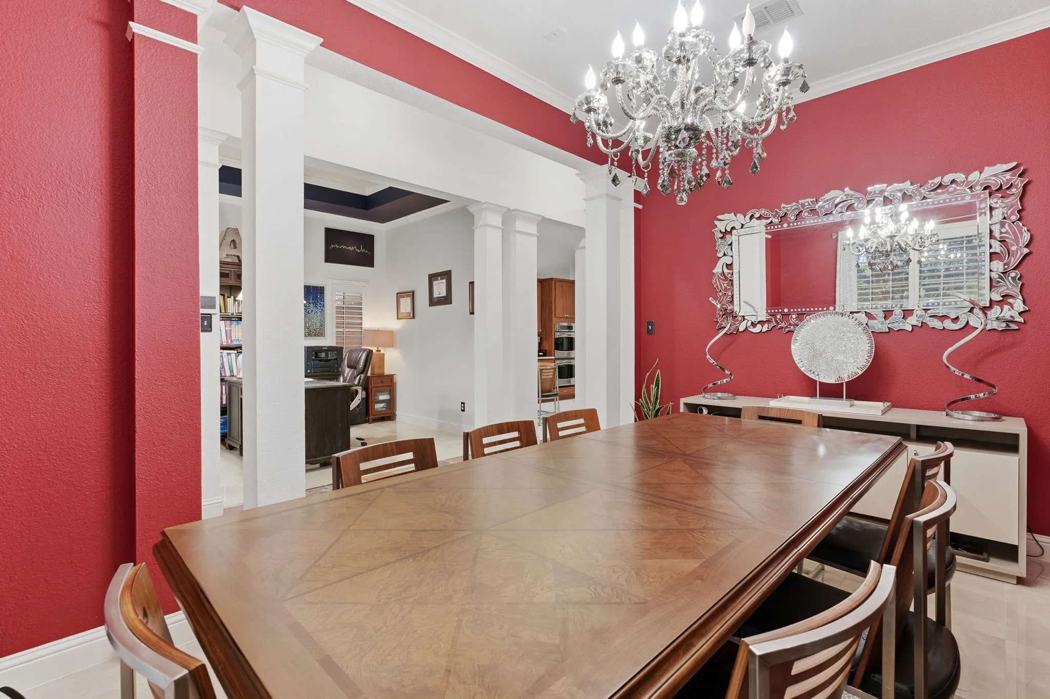 Spacious room with crown molding, chandelier lighting, and a decorative wall mirror