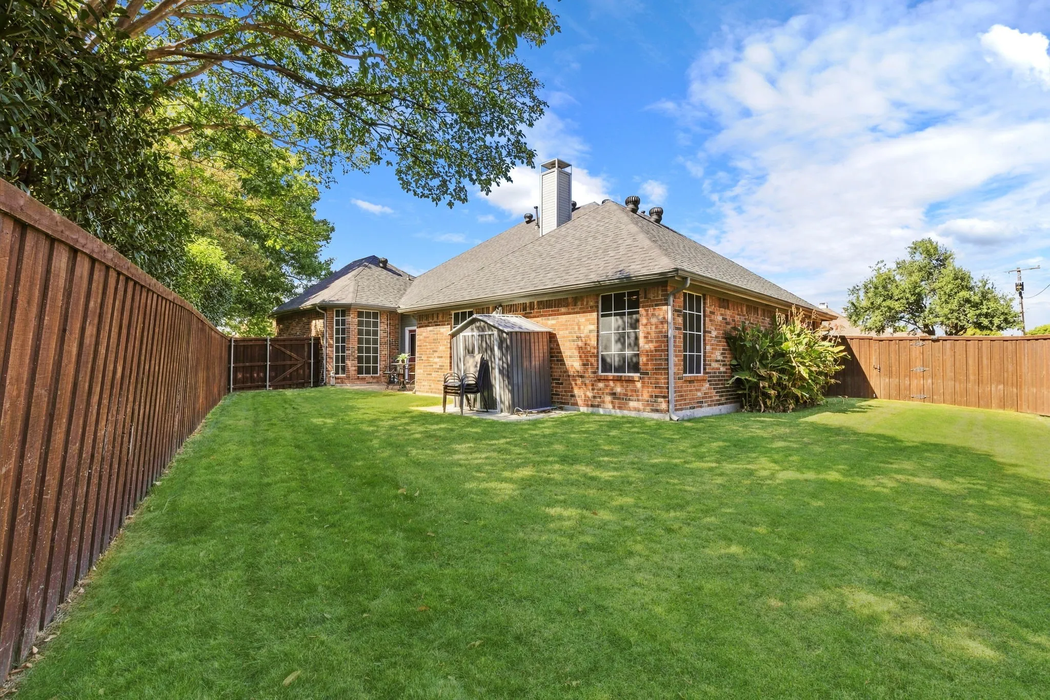 Expansive backyard with a manicured lawn, full brick exterior, and a privacy fence