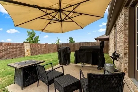 Expansive concrete patio with brick and stone privacy fencing and a manicured lawn