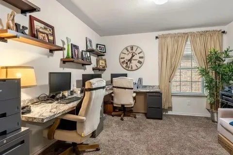 Room featuring built-in floating shelves, wall-mounted desk surfaces, a window with blinds and drapes, and carpeted flooring