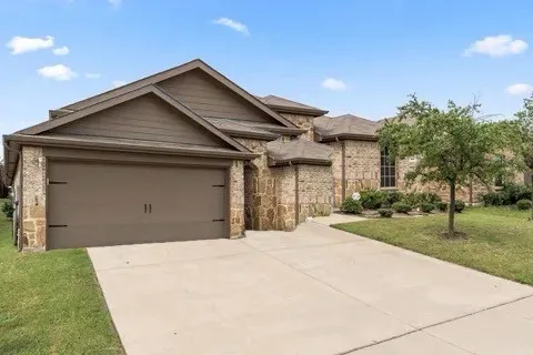 Stone and siding exterior with a gabled roofline, concrete driveway, and attached garage