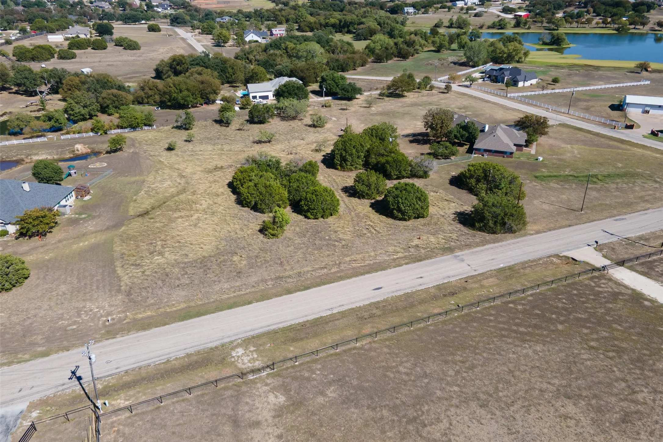 Expansive undeveloped lot with scattered mature trees and paved road frontage